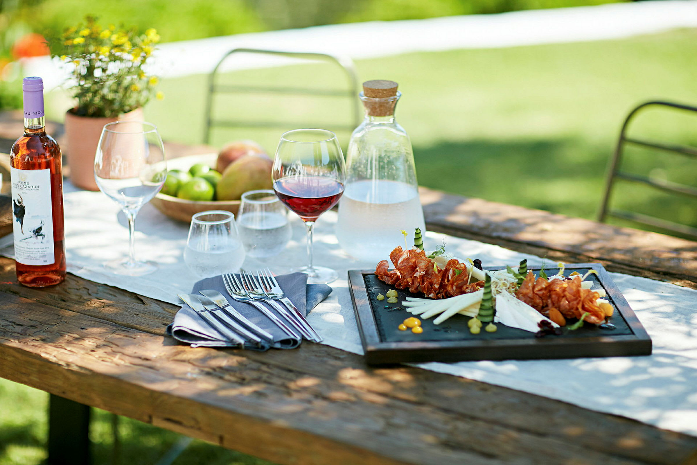 Matbord utomhus med tallrik, glas och en flaska vin. (AI-genererad text)