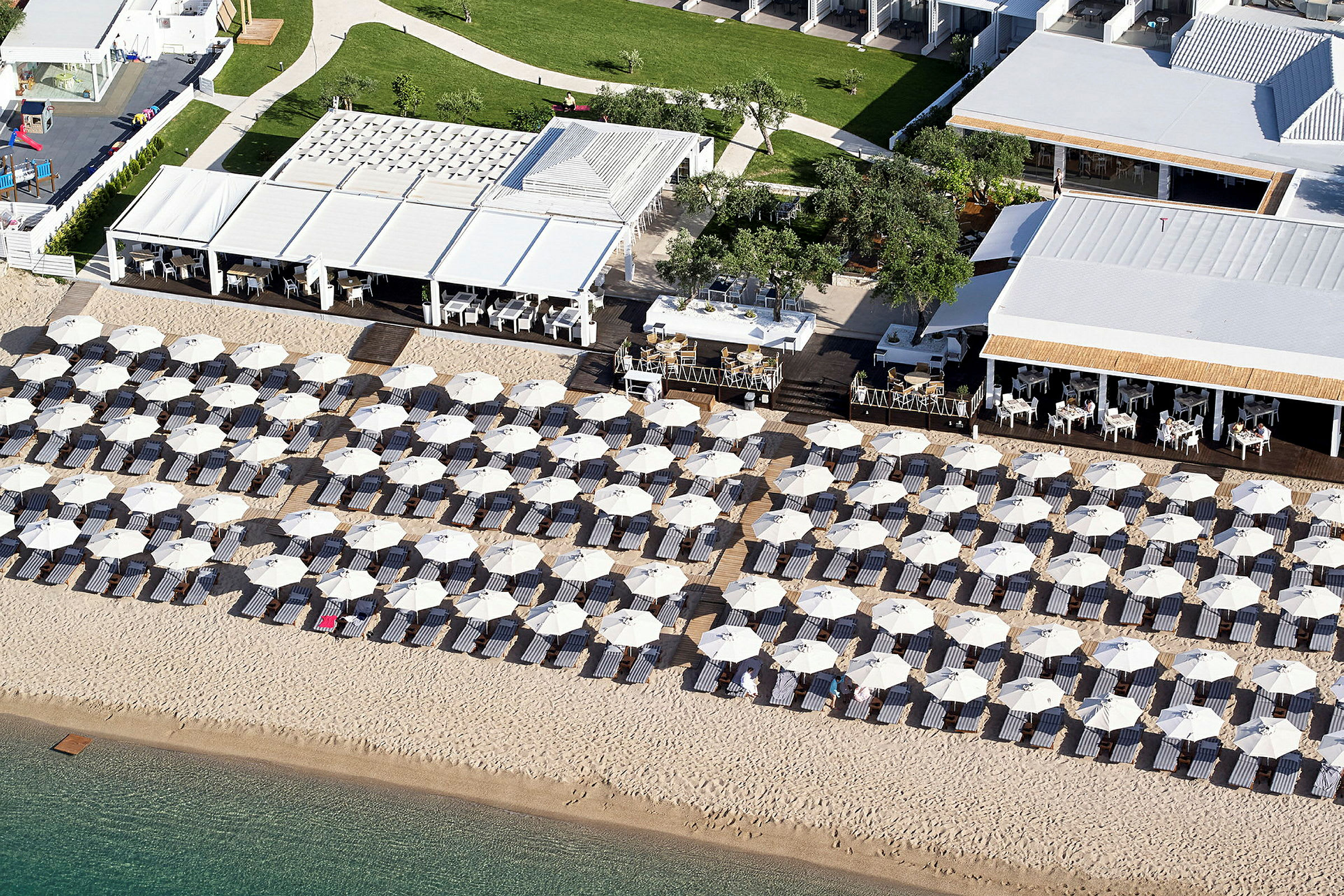 Vy över parasoller och solstolar på en sandstrand vid en resort. (AI-genererad text)