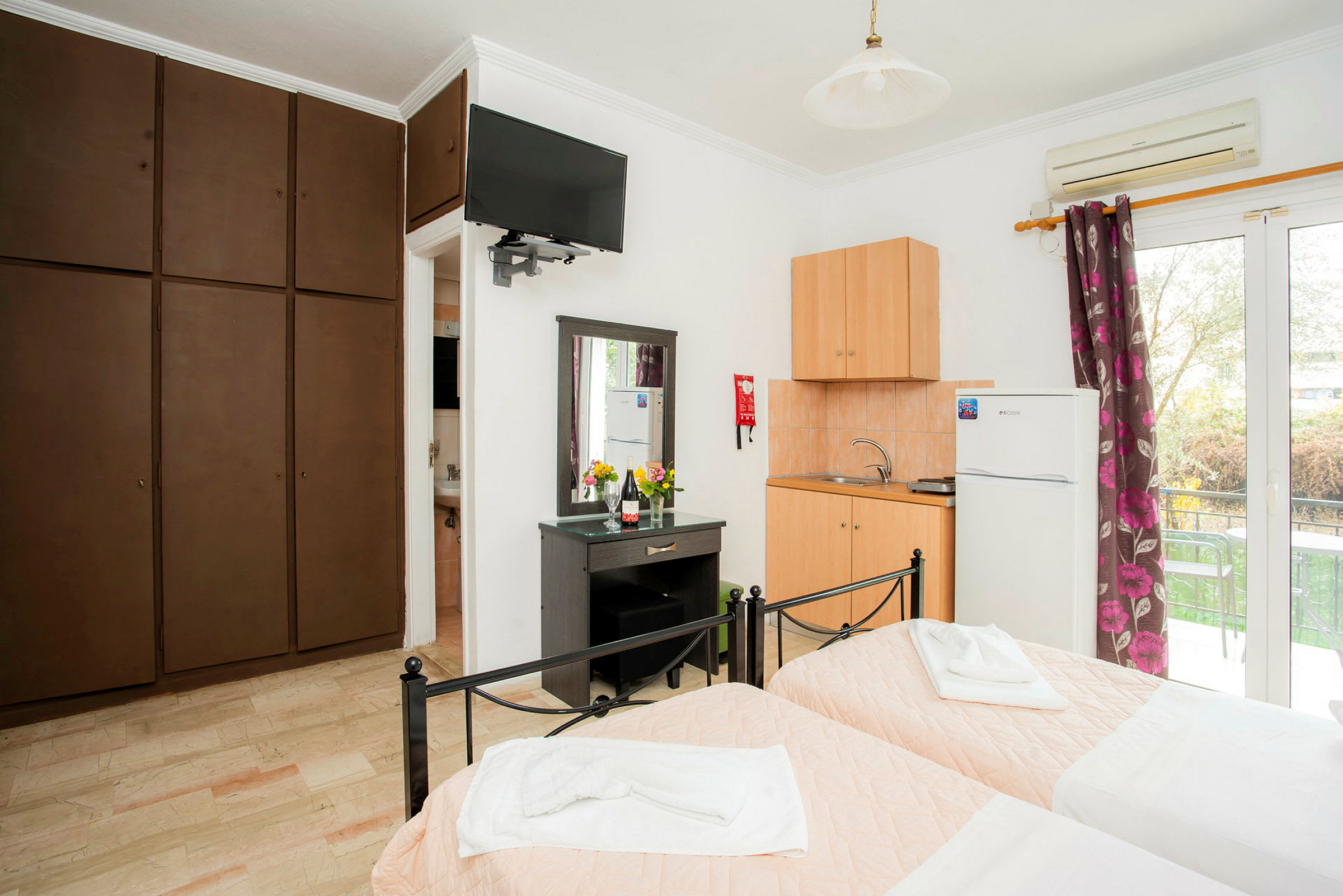 Hotellrum med två enkelsängar, kök, garderober och fönster. (AI-genererad text)