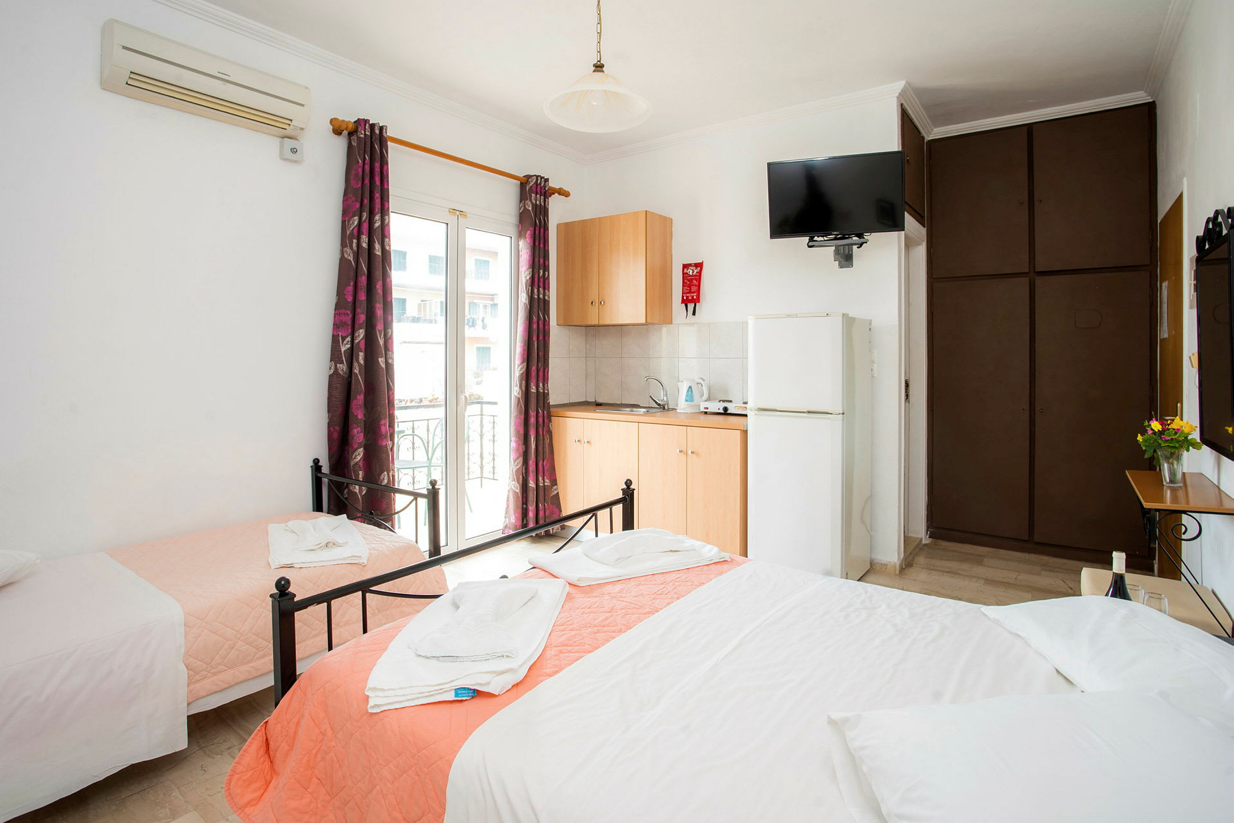 Hotellrum med tre bäddar, garderob, luftkonditionering och pentry. (AI-genererad text)