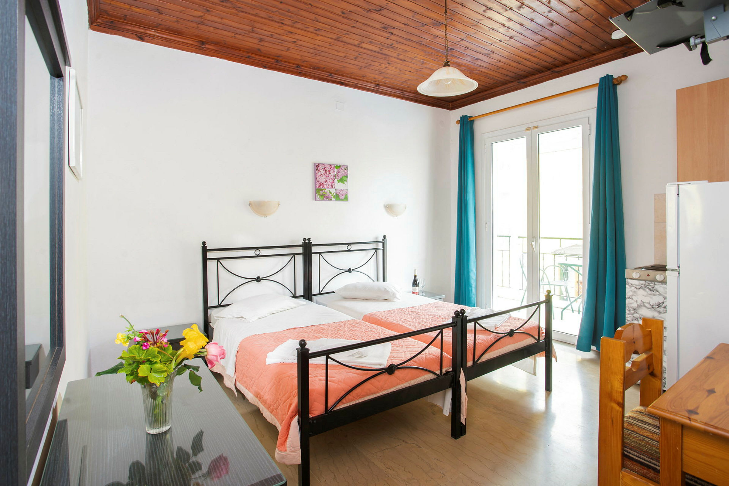 Ett hotellrum med två enkelsängar och en vas med blommor på ett bord. (AI-genererad text)