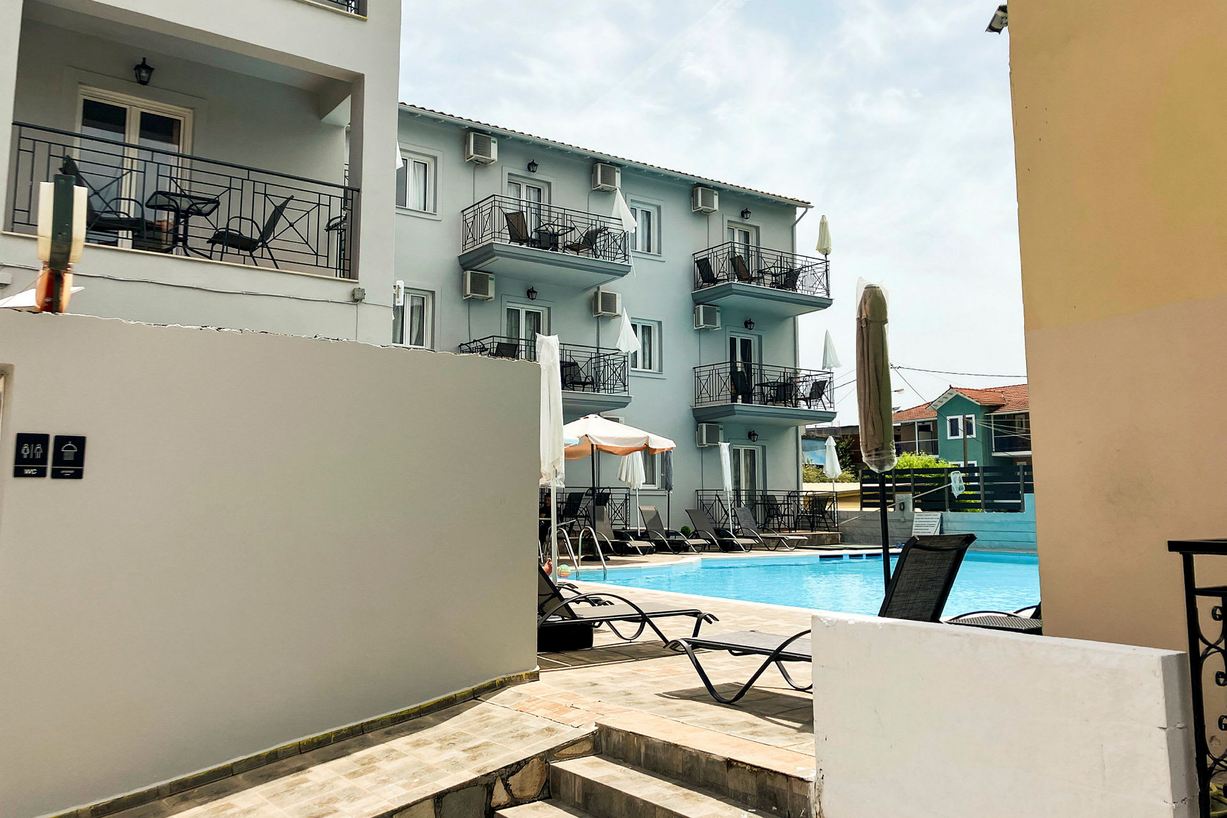 Hotellbyggnad med balkonger och en pool framför. (AI-genererad text)