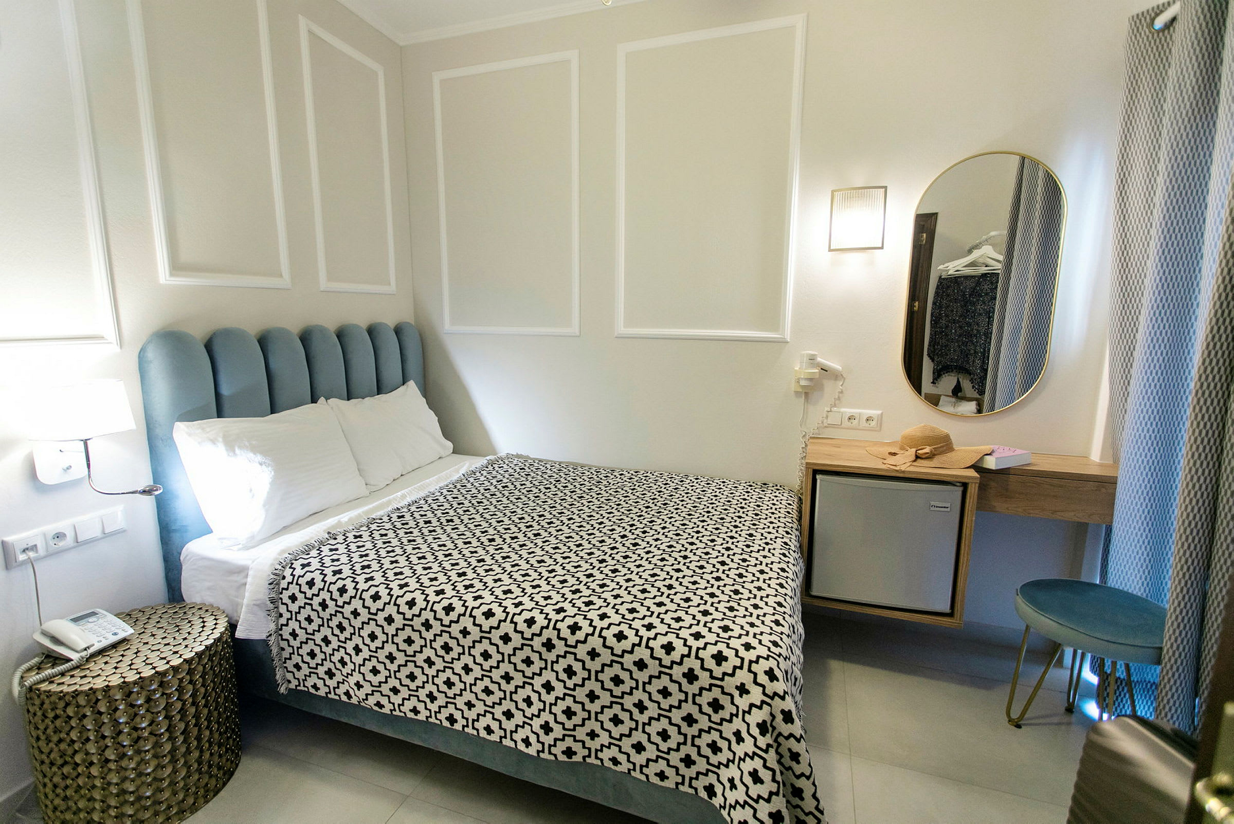 Ett hotellrum med en säng, ett nattduksbord och en spegel. (AI-genererad text)