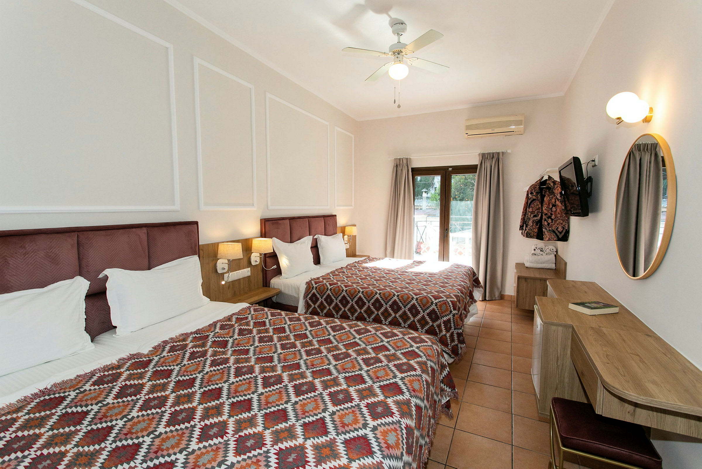 Hotellrum med två sängar och ett skrivbord, dekorerat med geometriska mönstrade överkast. (AI-genererad text)