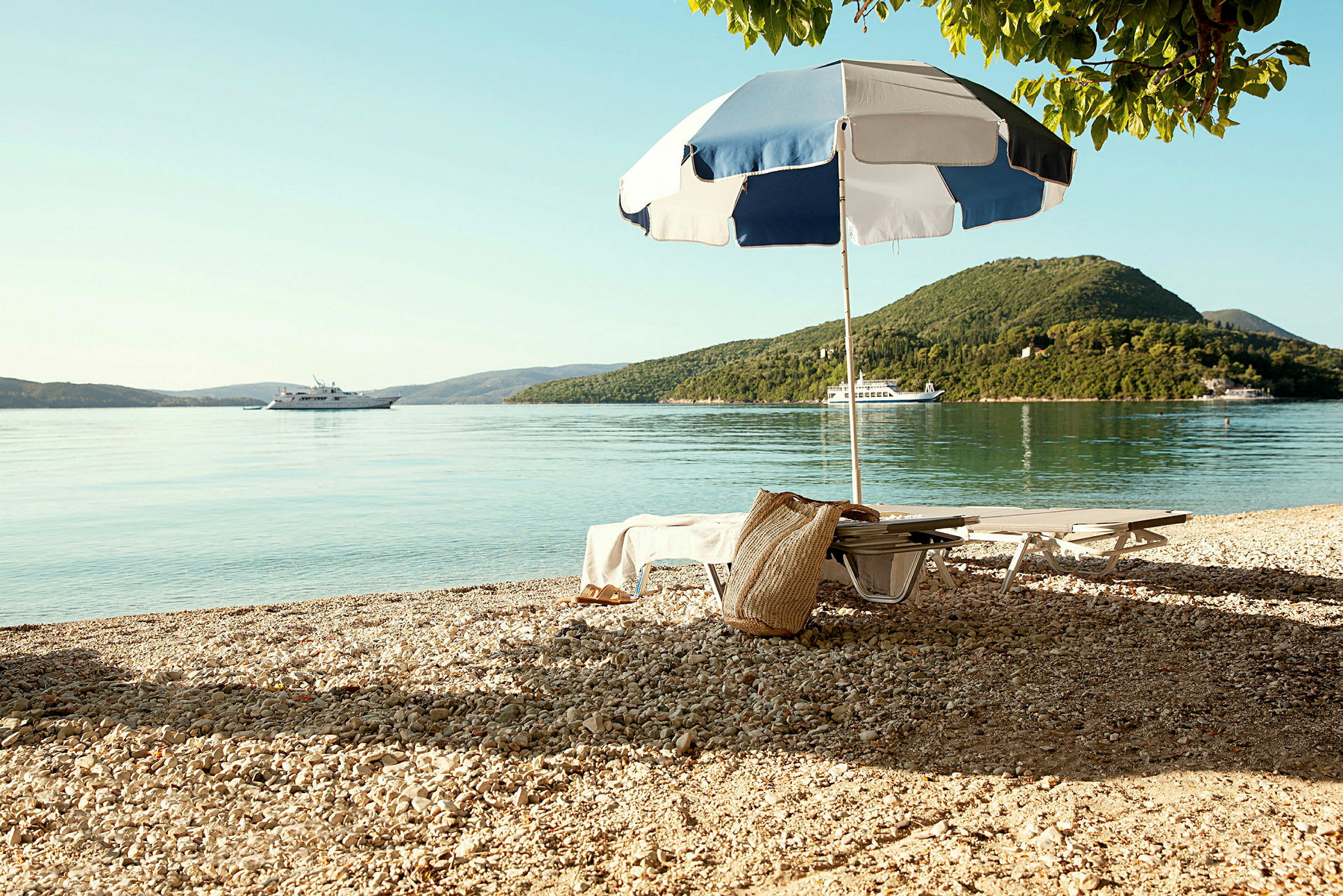 Strand med solstolar, parasoll och en båt på vattnet. (AI-genererad text)
