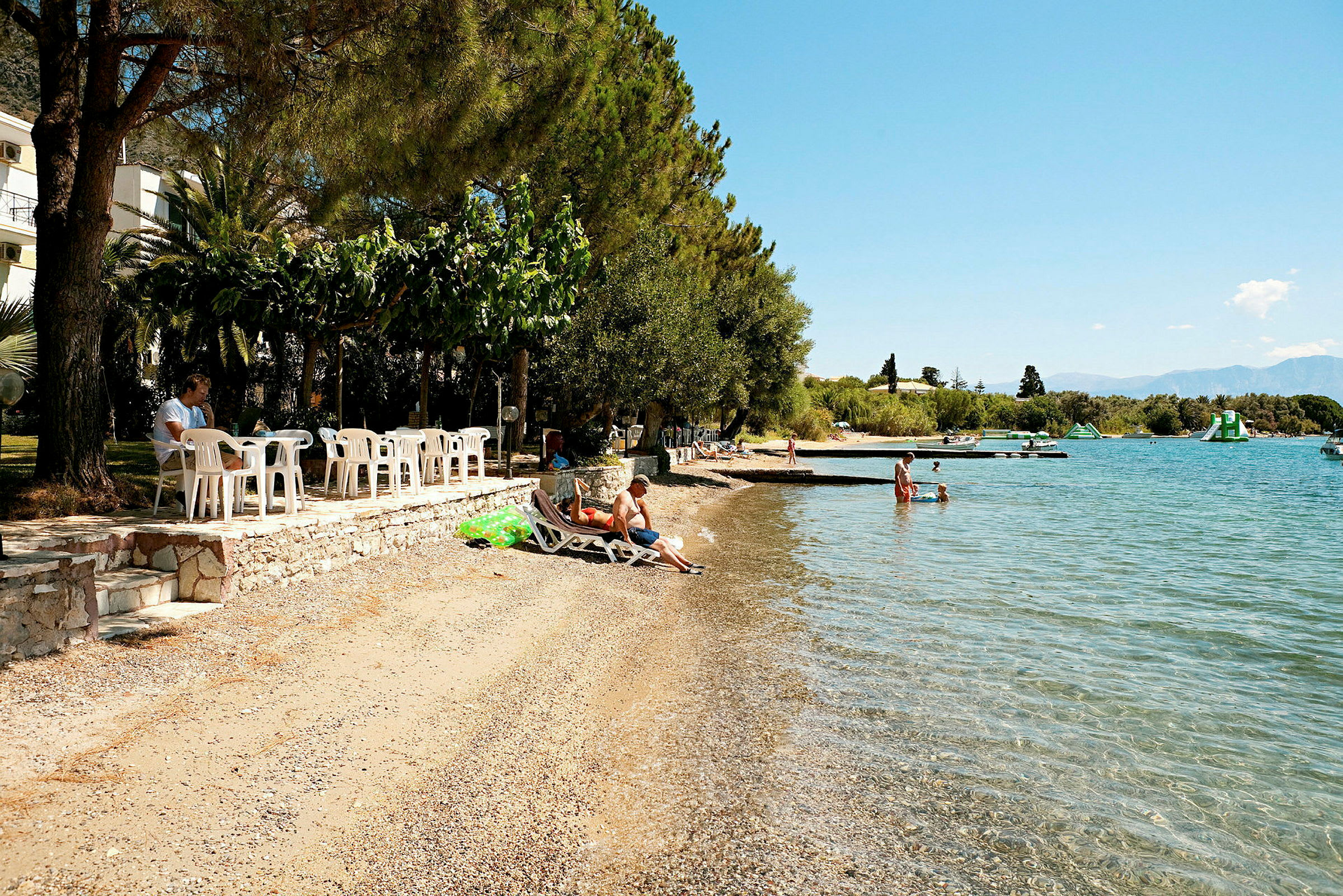En strand med solstolar, badbrygga och klara blått vatten. (AI-genererad text)