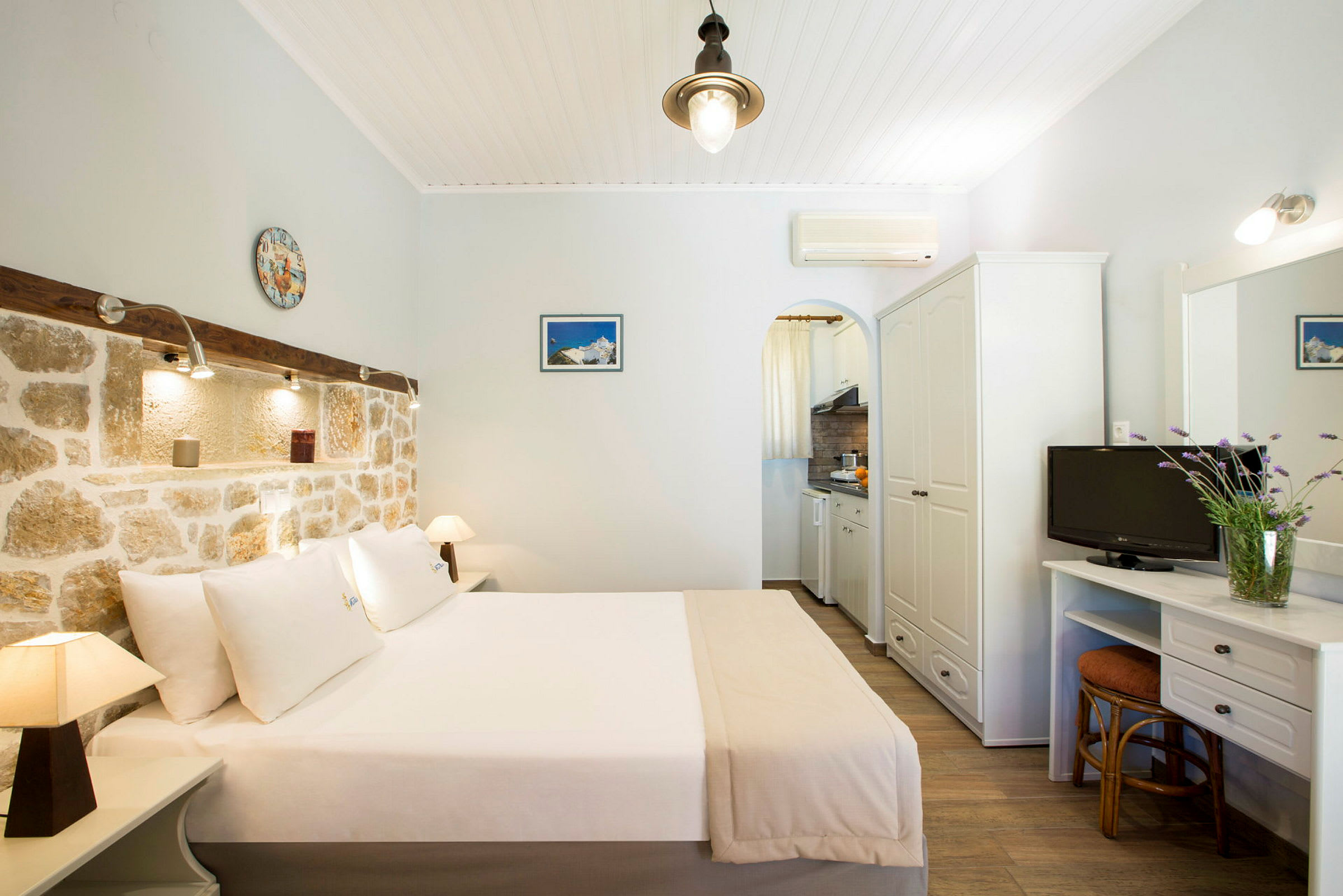 Hotellrum med dubbelsäng, stenmur och mindre köksdel. (AI-genererad text)