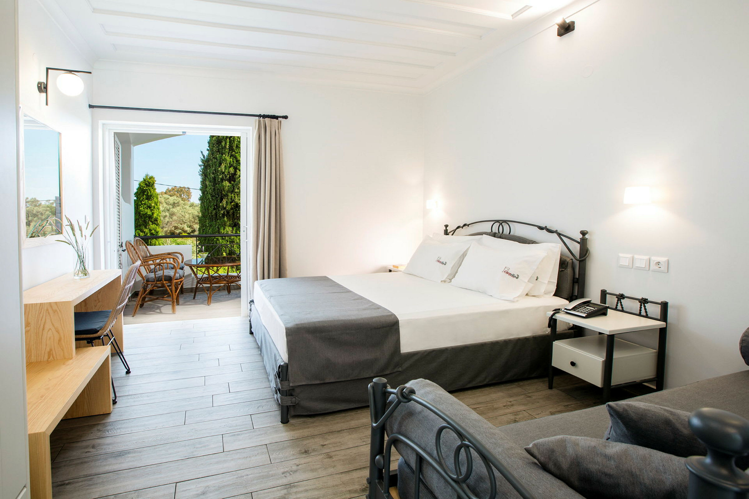 Modernt hotellrum med säng, skrivbord och utgång till möblerad balkong. (AI-genererad text)