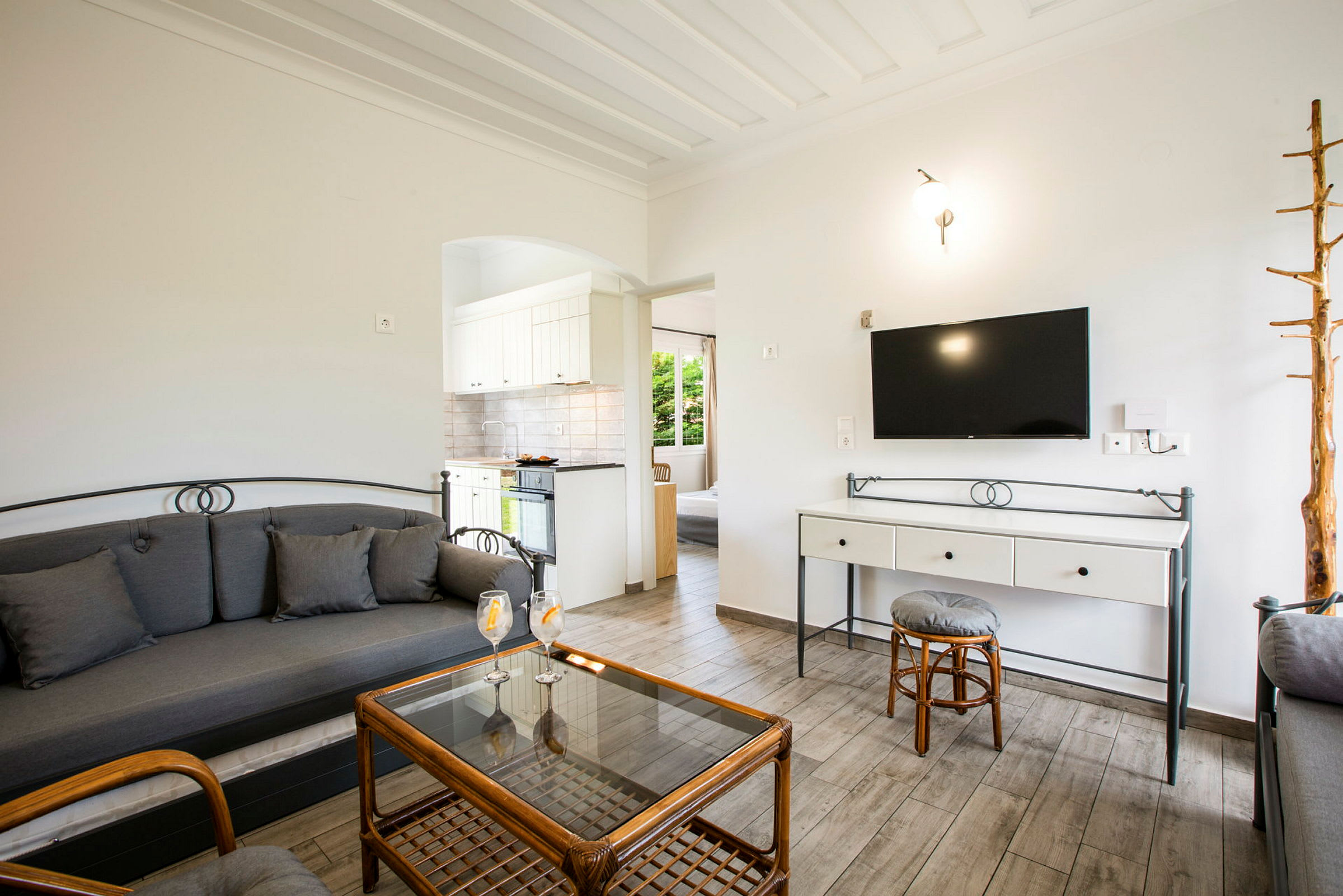 Vardagsrum med soffa, glasbord och en TV på väggen. (AI-genererad text)