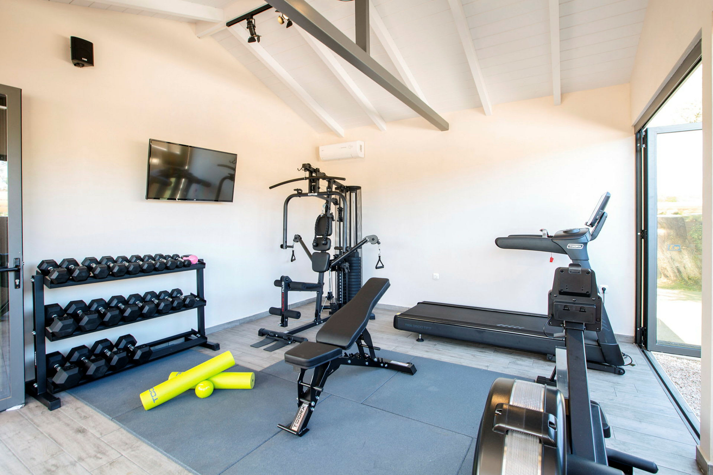 Ett gym med träningsutrustning inklusive hantlar, en löpmaskin och en träningsbänk. (AI-genererad text)