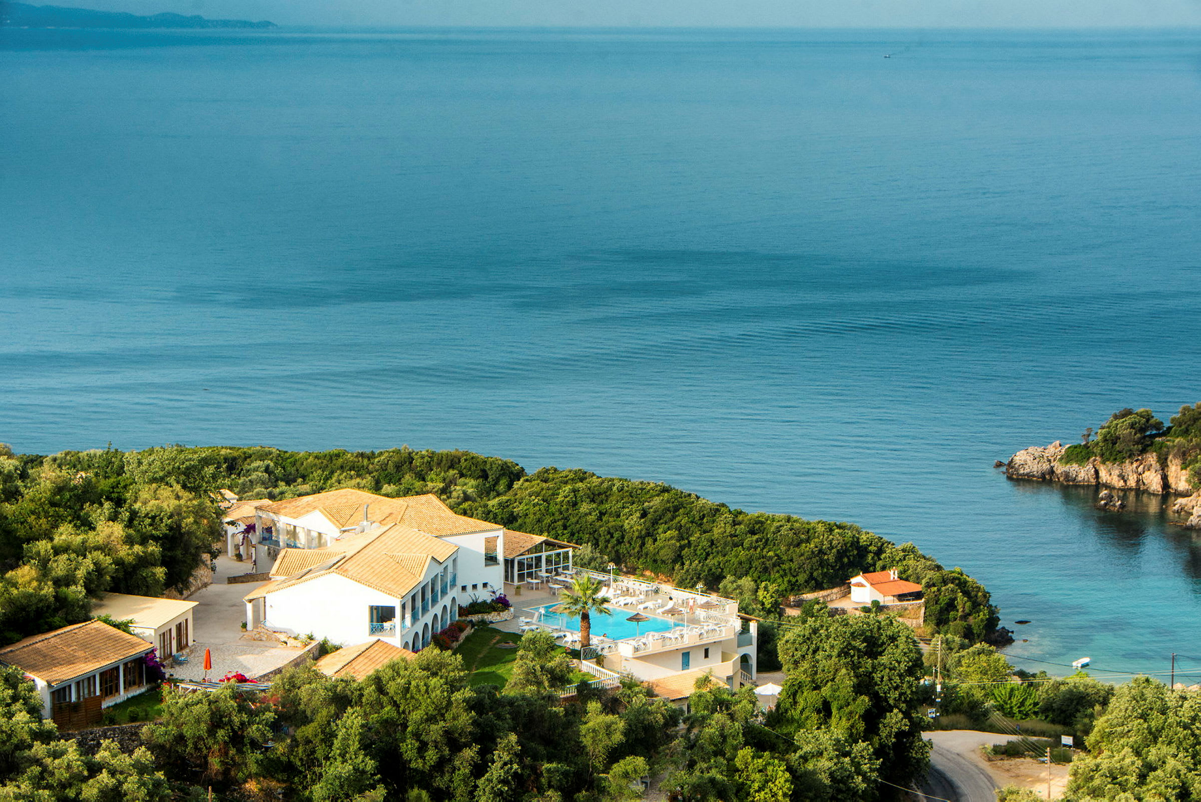 Hotellbyggnad med pool och omgivande grönska vid havet. (AI-genererad text)