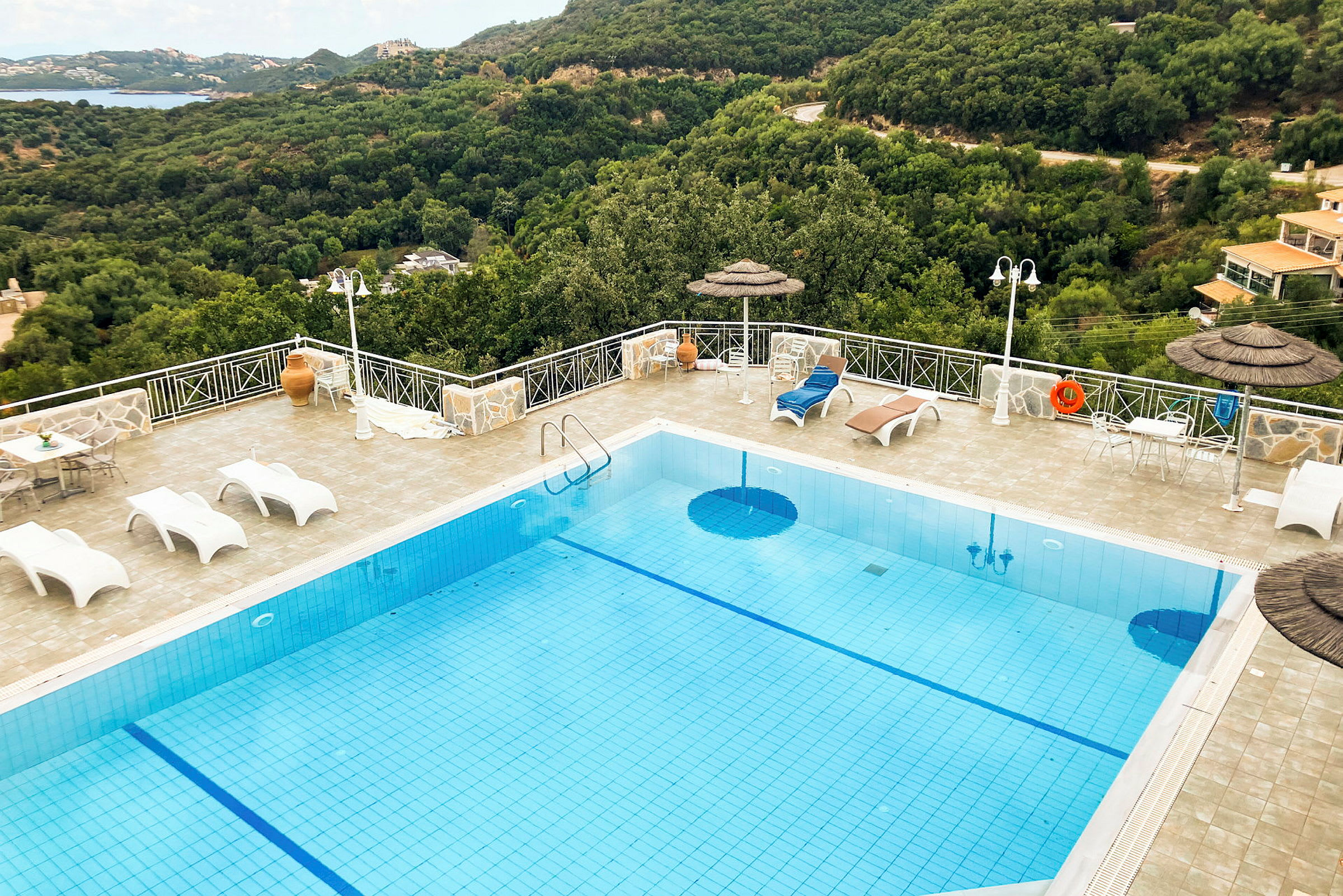Swimmingpool med solstolar och utsikt över grönskande kullar. (AI-genererad text)