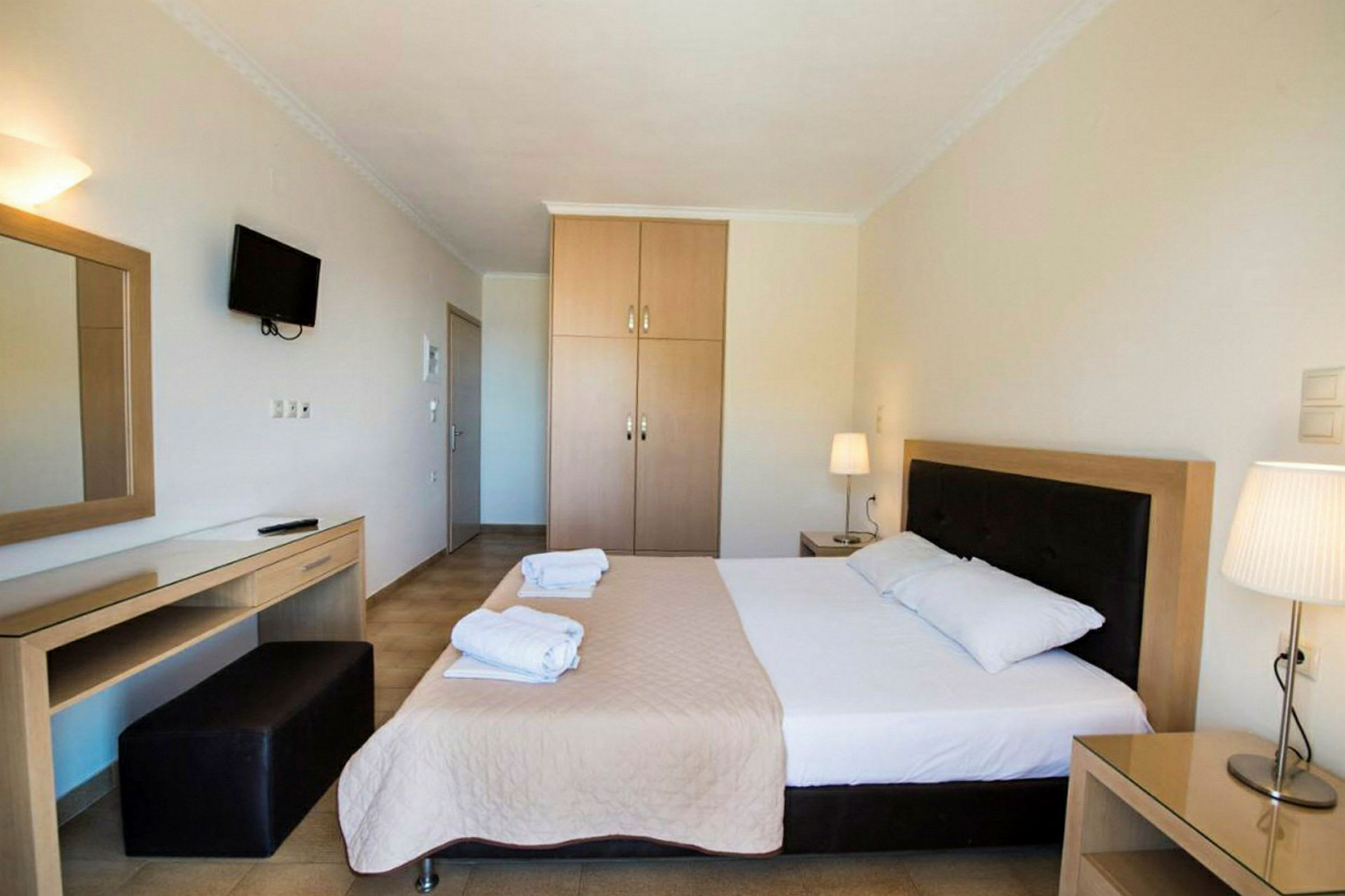Hotellrum med en dubbelsäng, nattduksbord, garderob och skrivbord. (AI-genererad text)