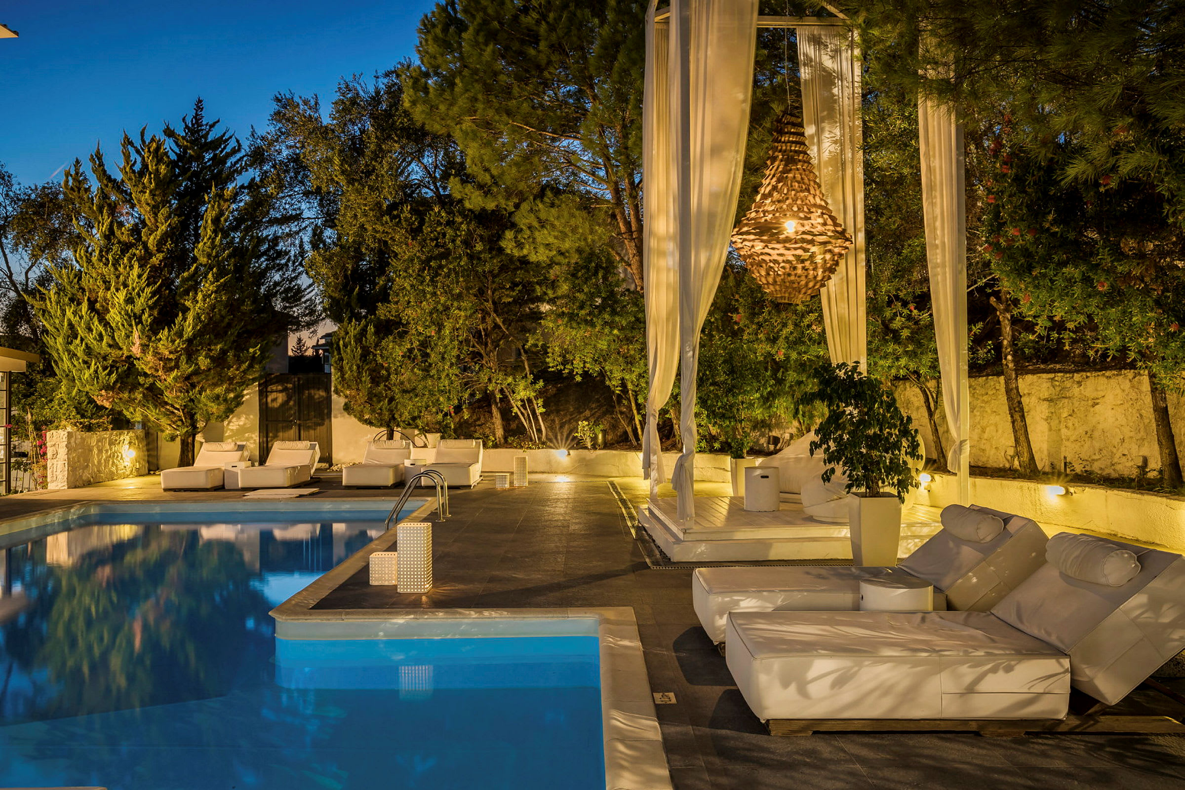 Utemiljö med pool, solstolar och belysning. (AI-genererad text)
