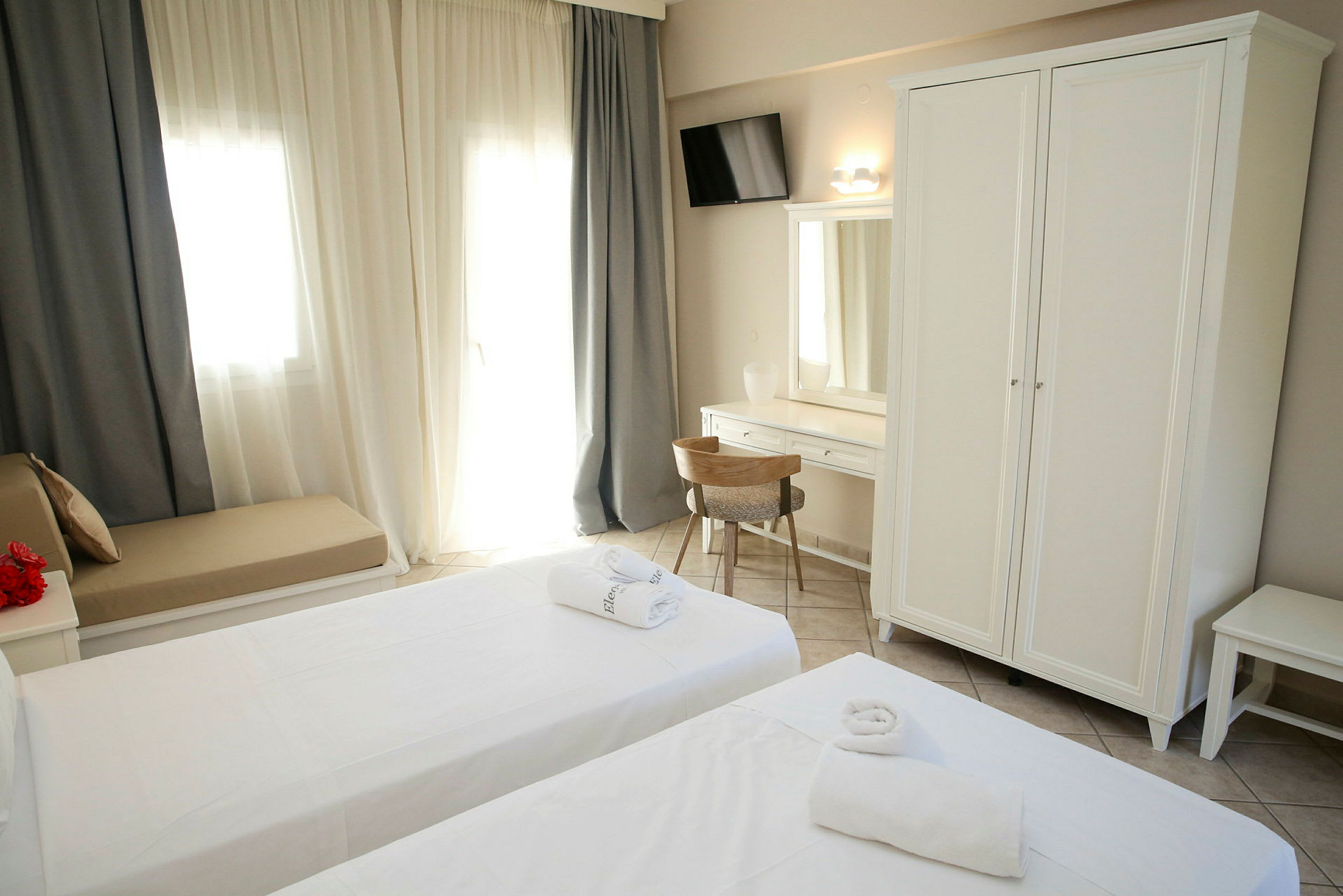 Bild av ett hotellrum med två sängar, vit garderob och skrivbord. (AI-genererad text)