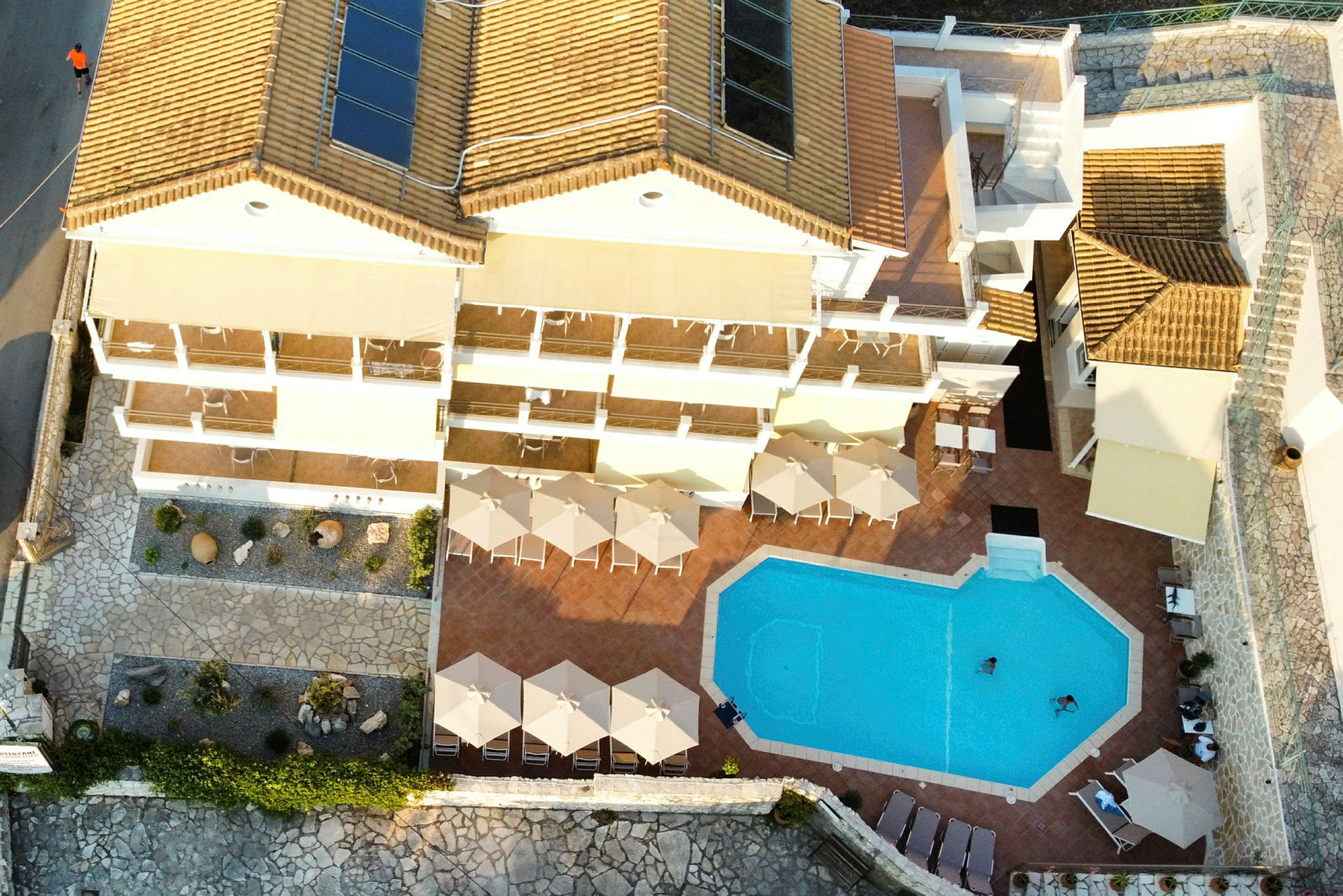 Ett fågelperspektiv av ett hotellområde med en pool och solparasoller. (AI-genererad text)