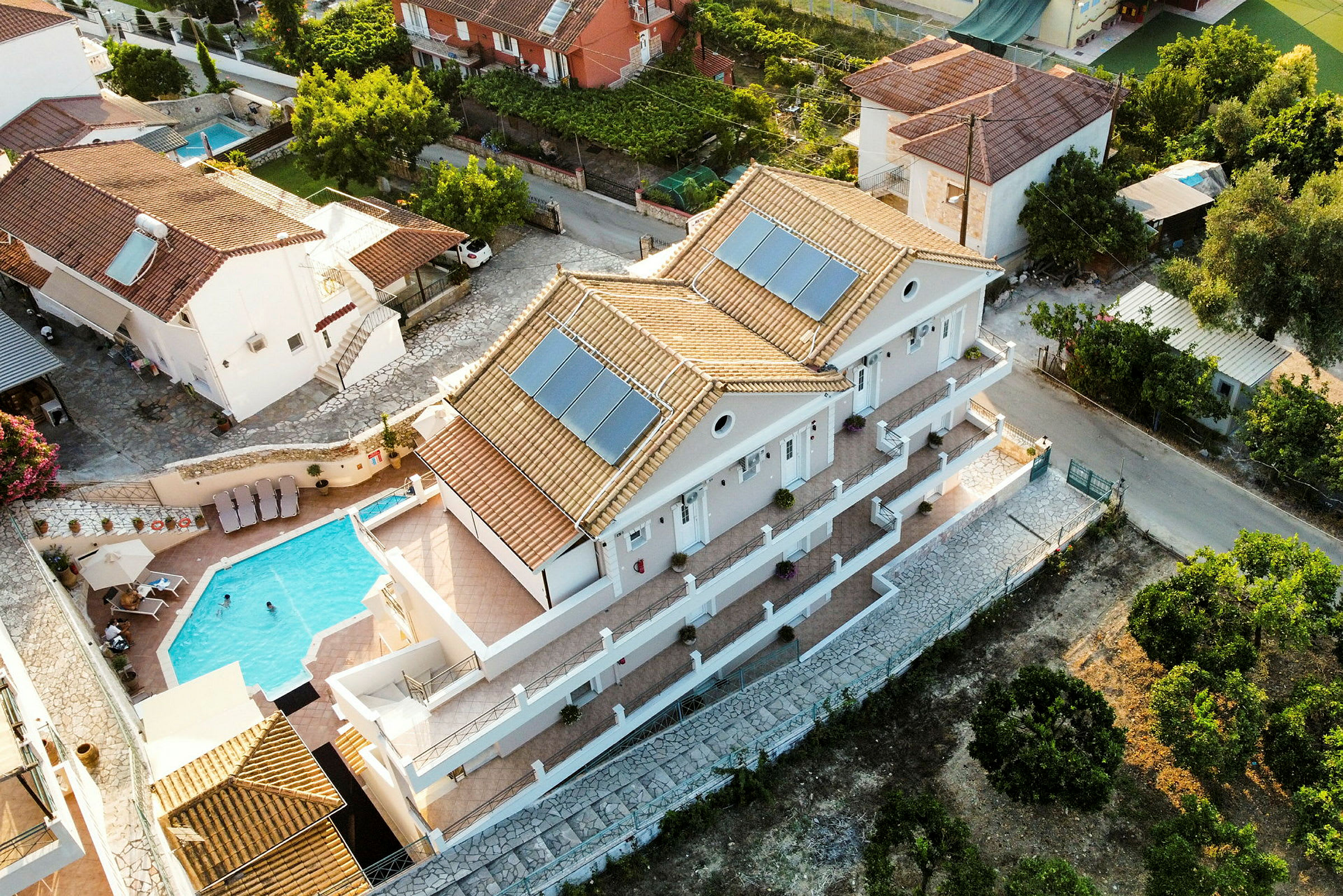 Flygfoto av villa med pool och omkringliggande hus. (AI-genererad text)