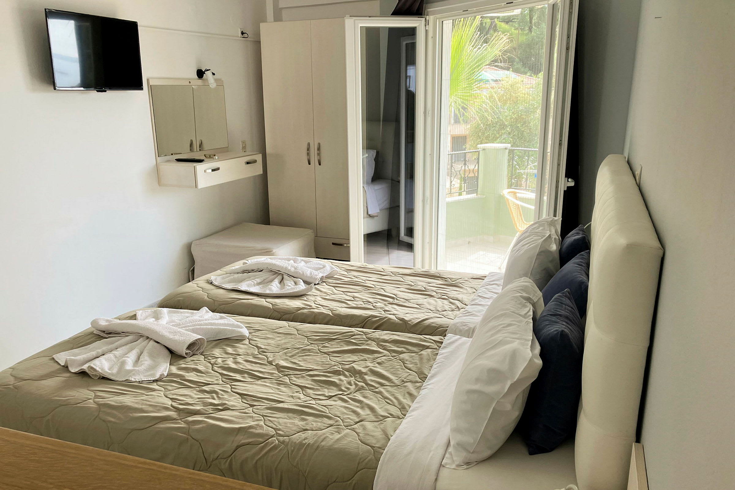 Hotellrum med två enkelsängar, garderob och öppen balkongdörr. (AI-genererad text)
