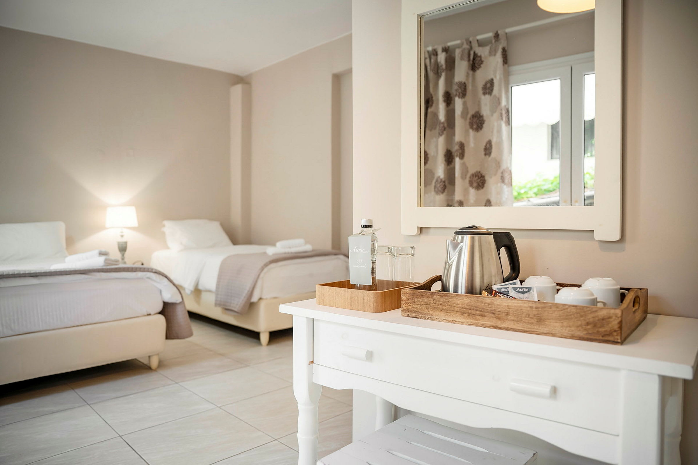 Ett hotellrum med två sängar och ett bord med vattenkokare och koppar. (AI-genererad text)