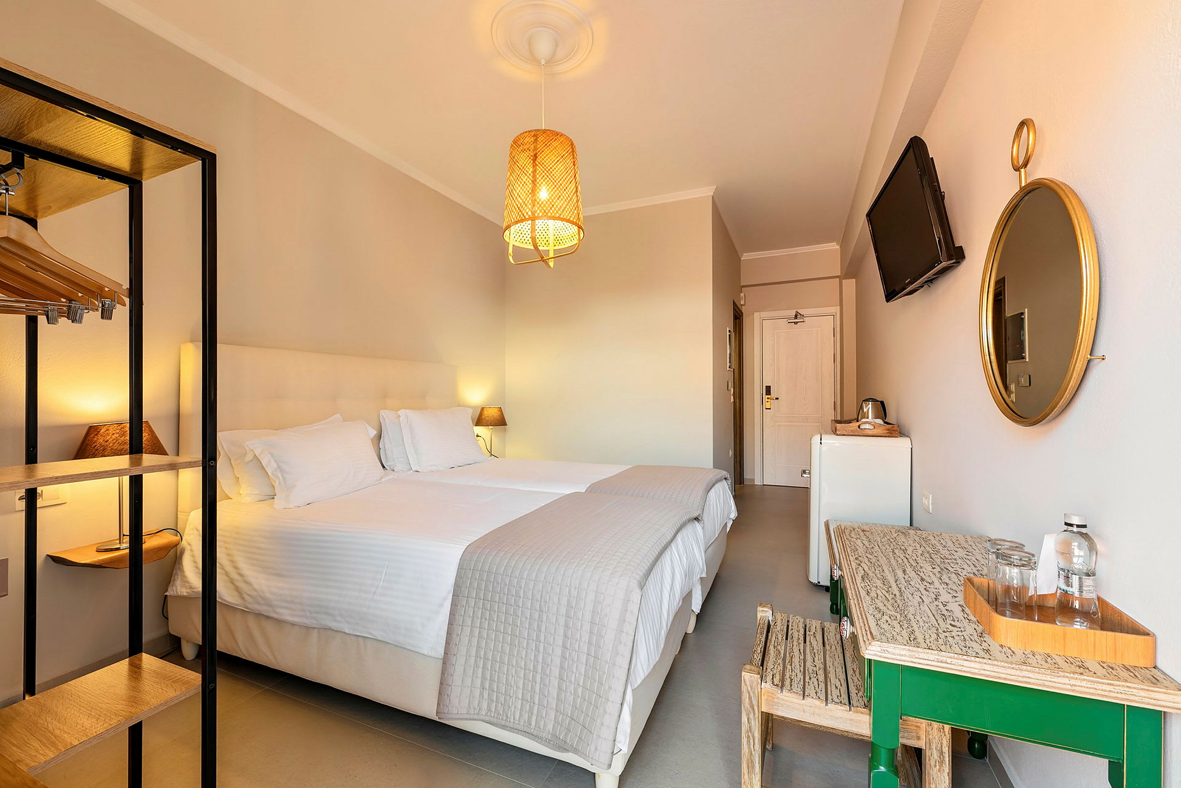 Ett hotellrum med två sängar, ett bord med vattenflaskor och ett väggmonterat spegel. (AI-genererad text)