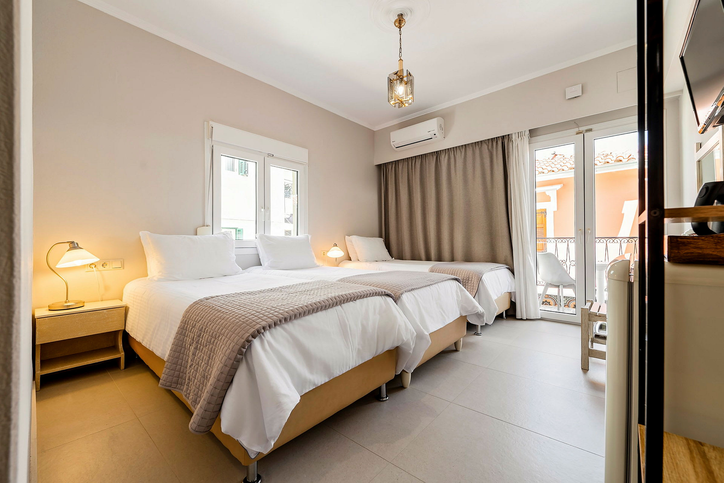 En interiör av ett hotellrum med tre sängar, lampor och fönster. (AI-genererad text)