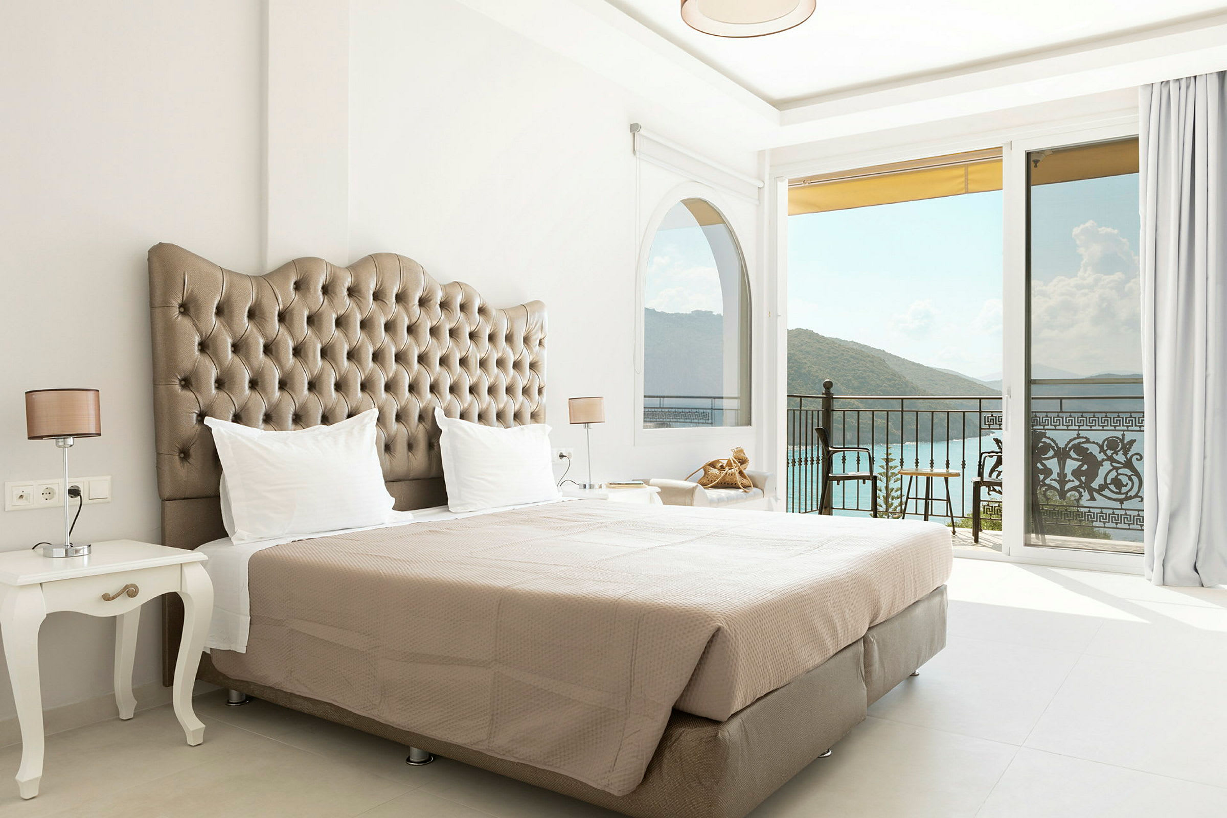 Hotellrum med en dubbelsäng och utsikt över havet genom stora fönster. (AI-genererad text)