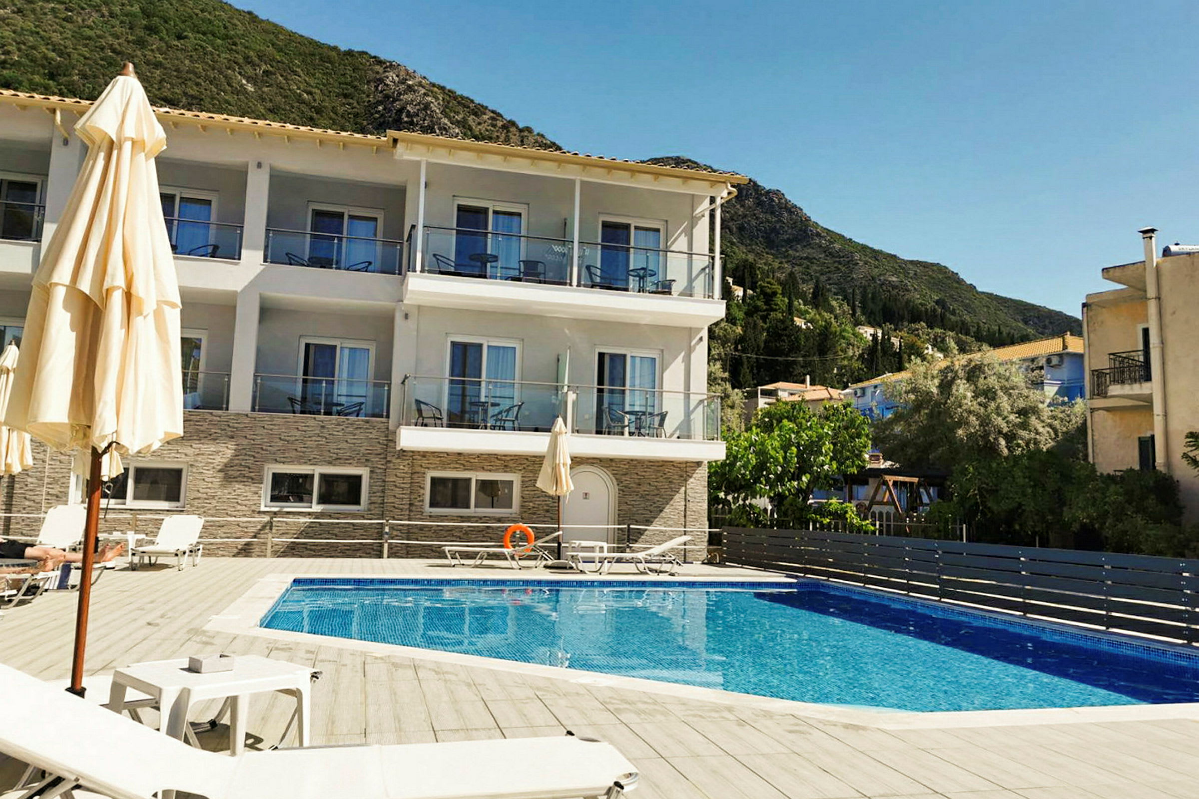 Hotellbyggnad med balkonger framför en pool. (AI-genererad text)