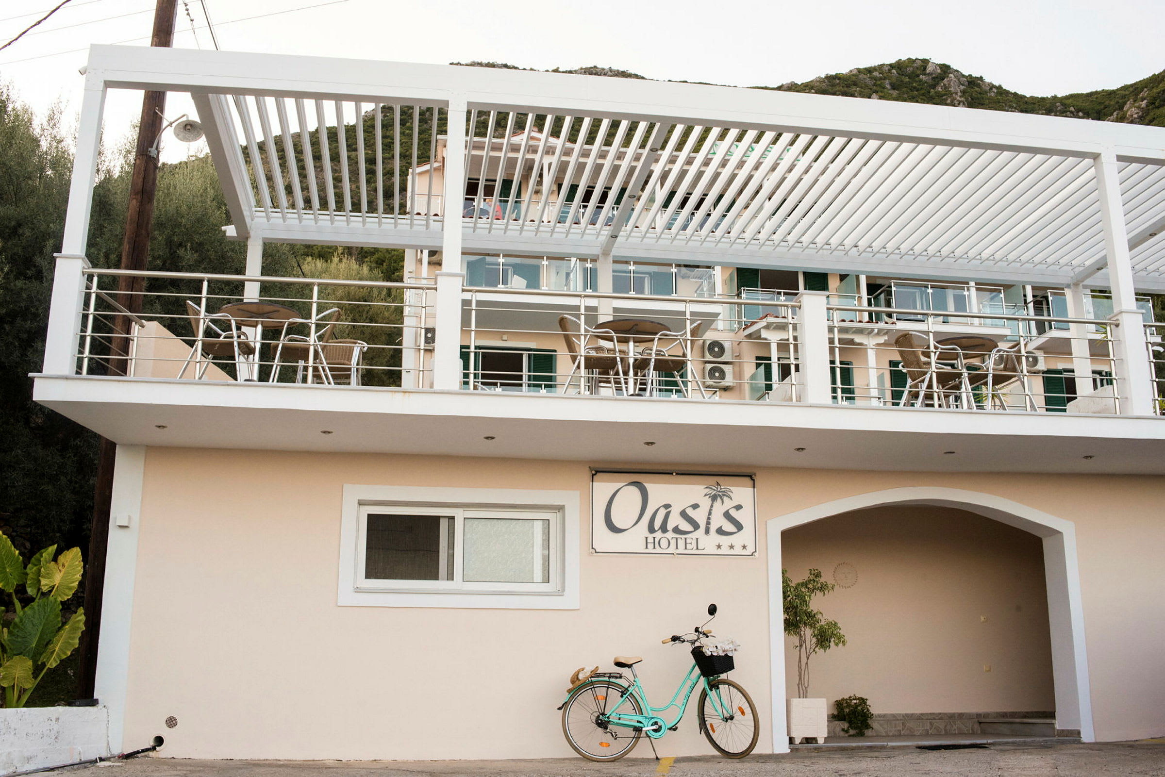 Bild av Oasis Hotel med balkonger och utemöbler samt en cykel parkerad nedanför. (AI-genererad text)
