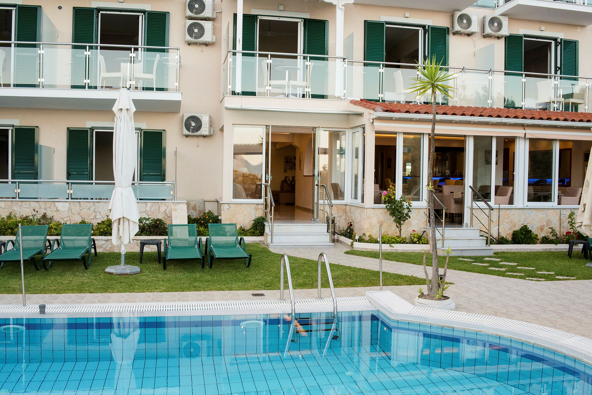 Utomhusområde med en pool, solstolar och ett lägenhetshus i bakgrunden. (AI-genererad text)