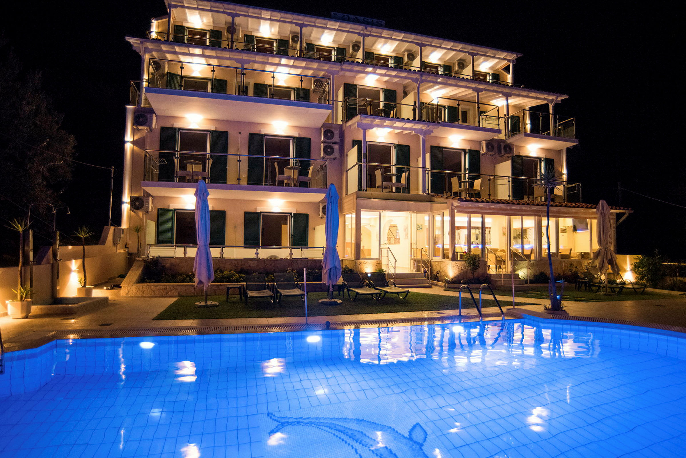 Hotellbyggnad med flera våningar och en upplyst pool i förgrunden under en mörk natthimmel. (AI-genererad text)