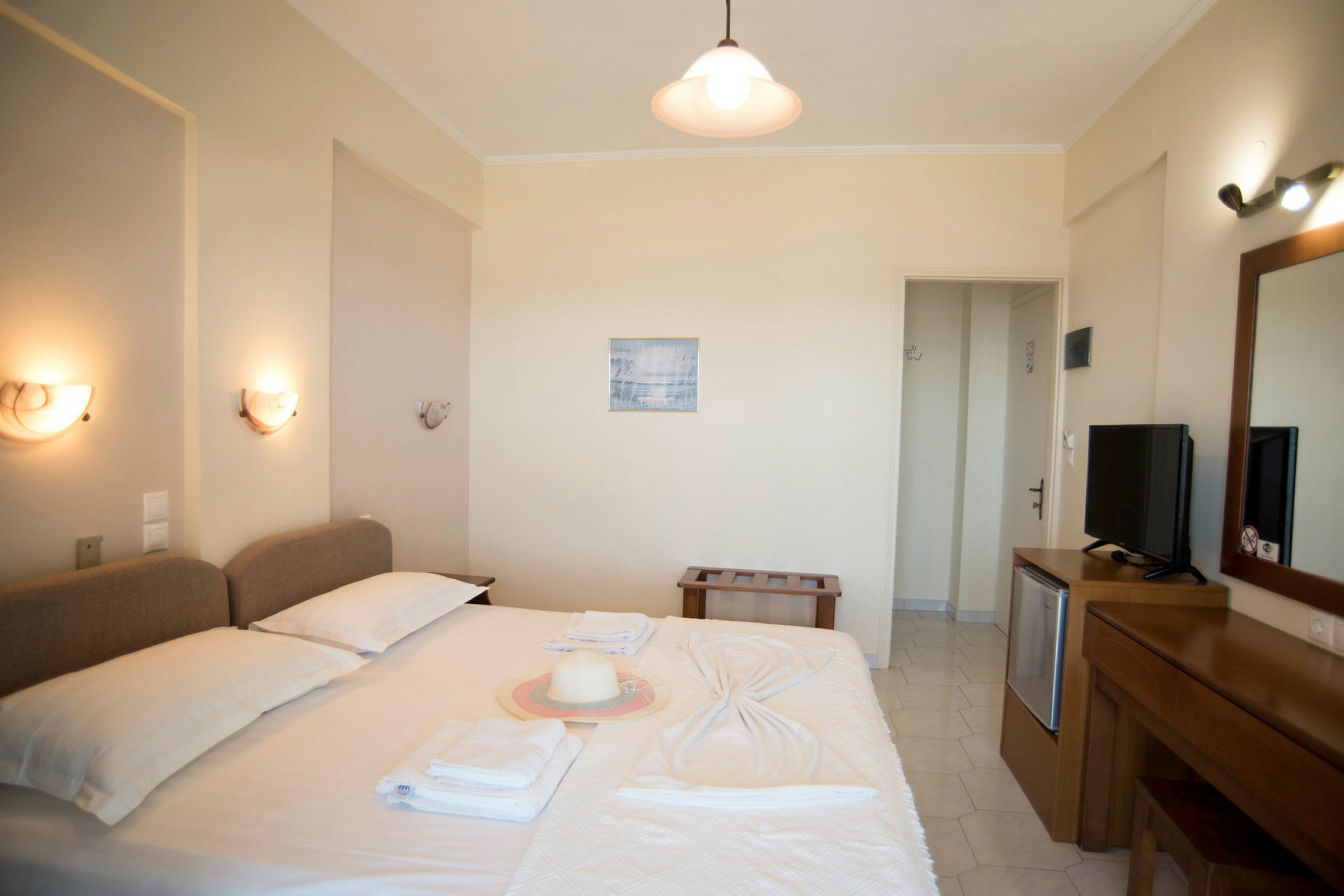 Ett hotellrum med en dubbelsäng, ett skrivbord, en TV och dekorerade väggar. (AI-genererad text)