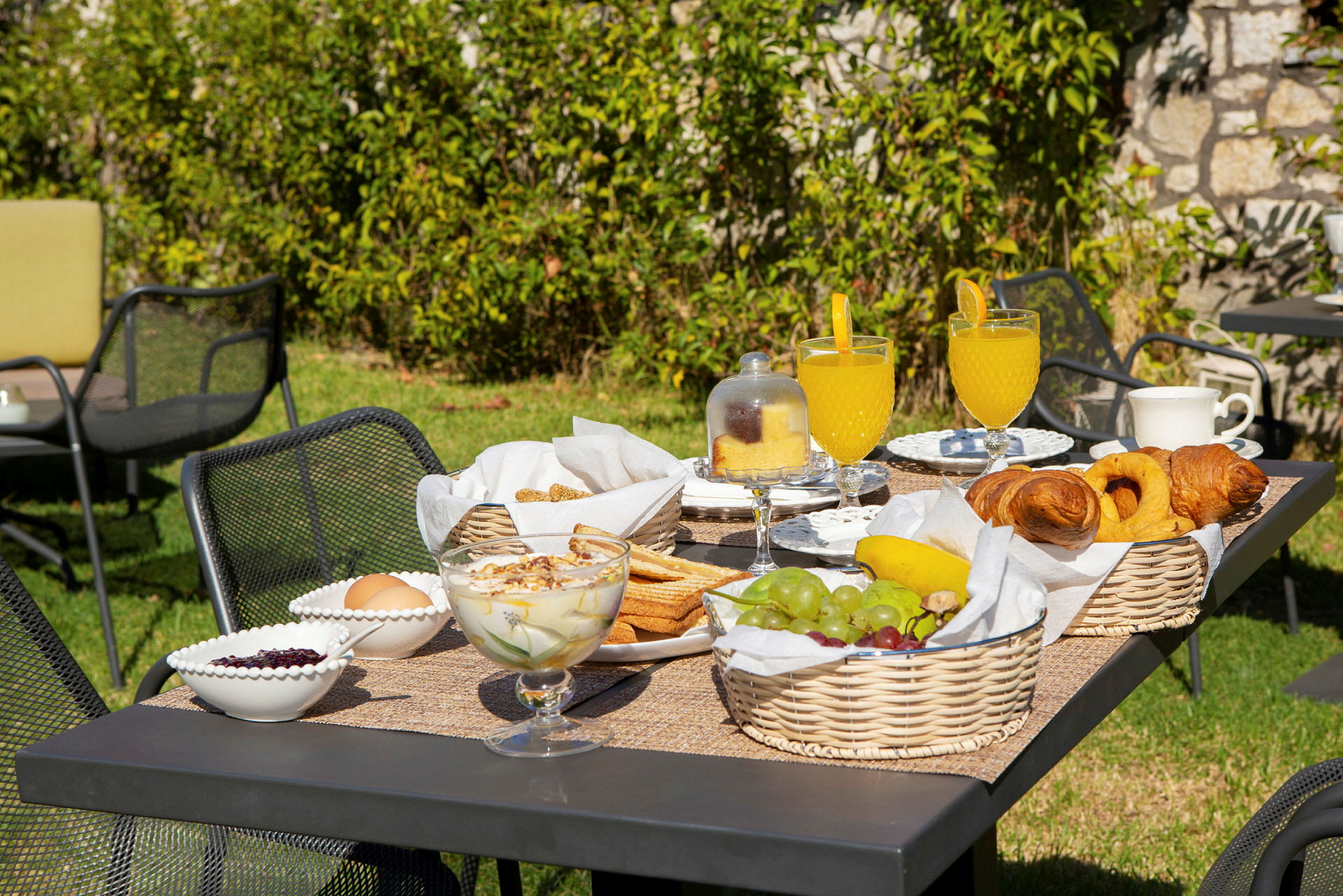 Trädgårdsbord med frukost innehållande frukt, bakverk och dryck. (AI-genererad text)