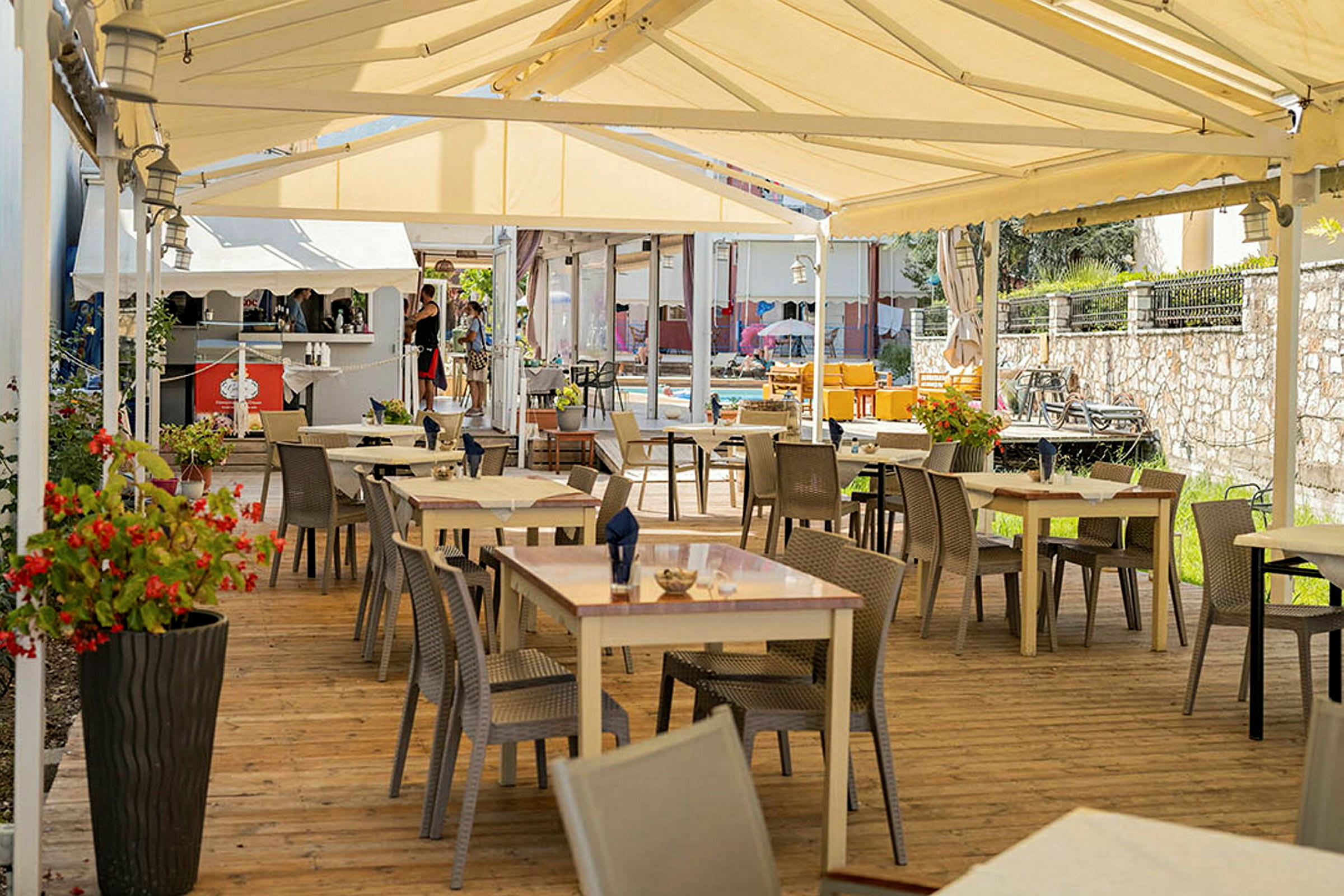 Utomhusrestaurang med bord och stolar under ett tält. (AI-genererad text)