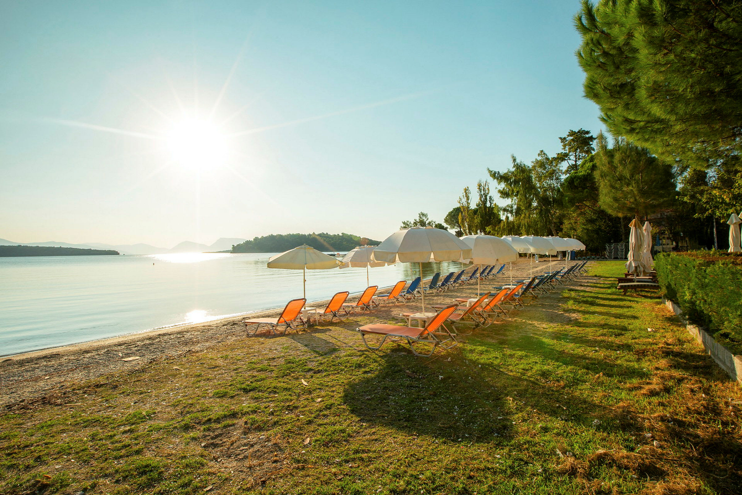 Strand med solstolar och parasoller vid soluppgång. (AI-genererad text)