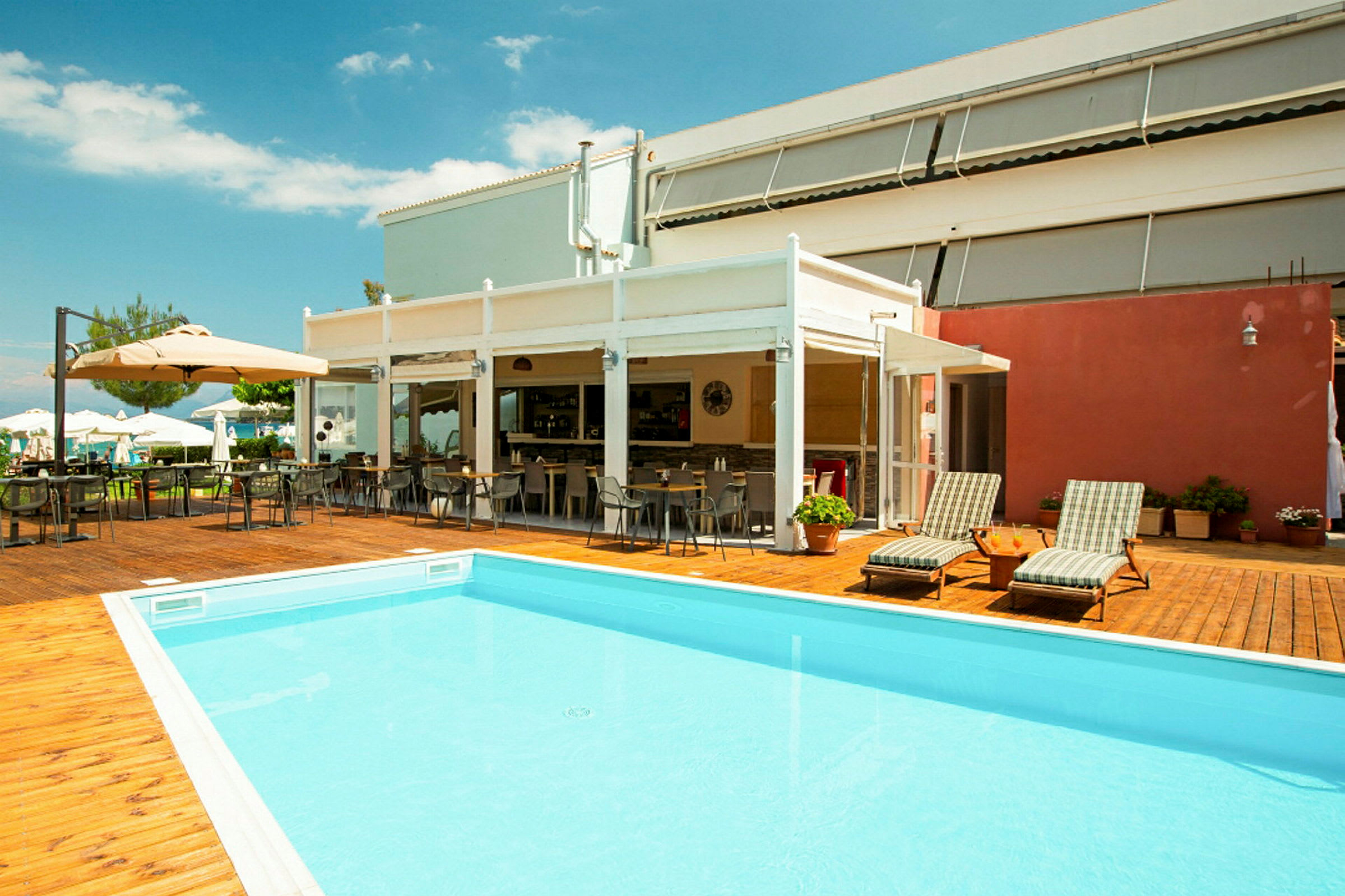 Utomhusområde med pool, solstolar och uteservering vid ett hotell. (AI-genererad text)