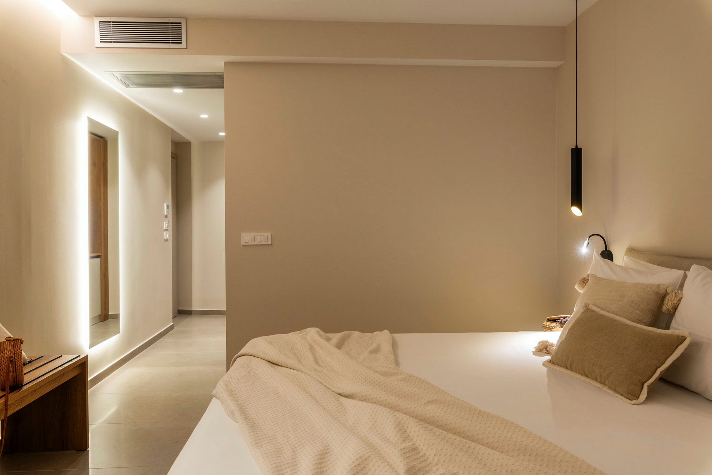 Ett modernt hotellrum med säng och mjuka kuddar samt minimalistisk belysning. (AI-genererad text)