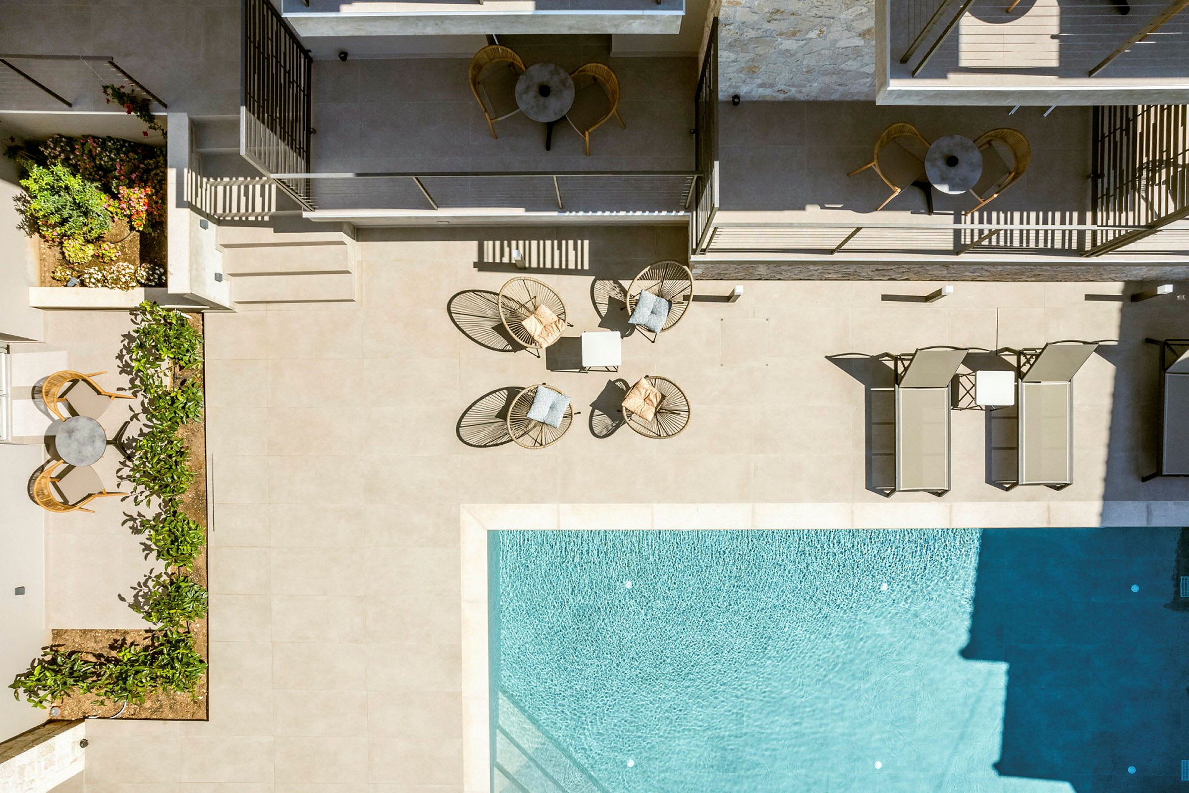 Utsikt ovanifrån av en solterrass med stolar och bord bredvid en pool. (AI-genererad text)