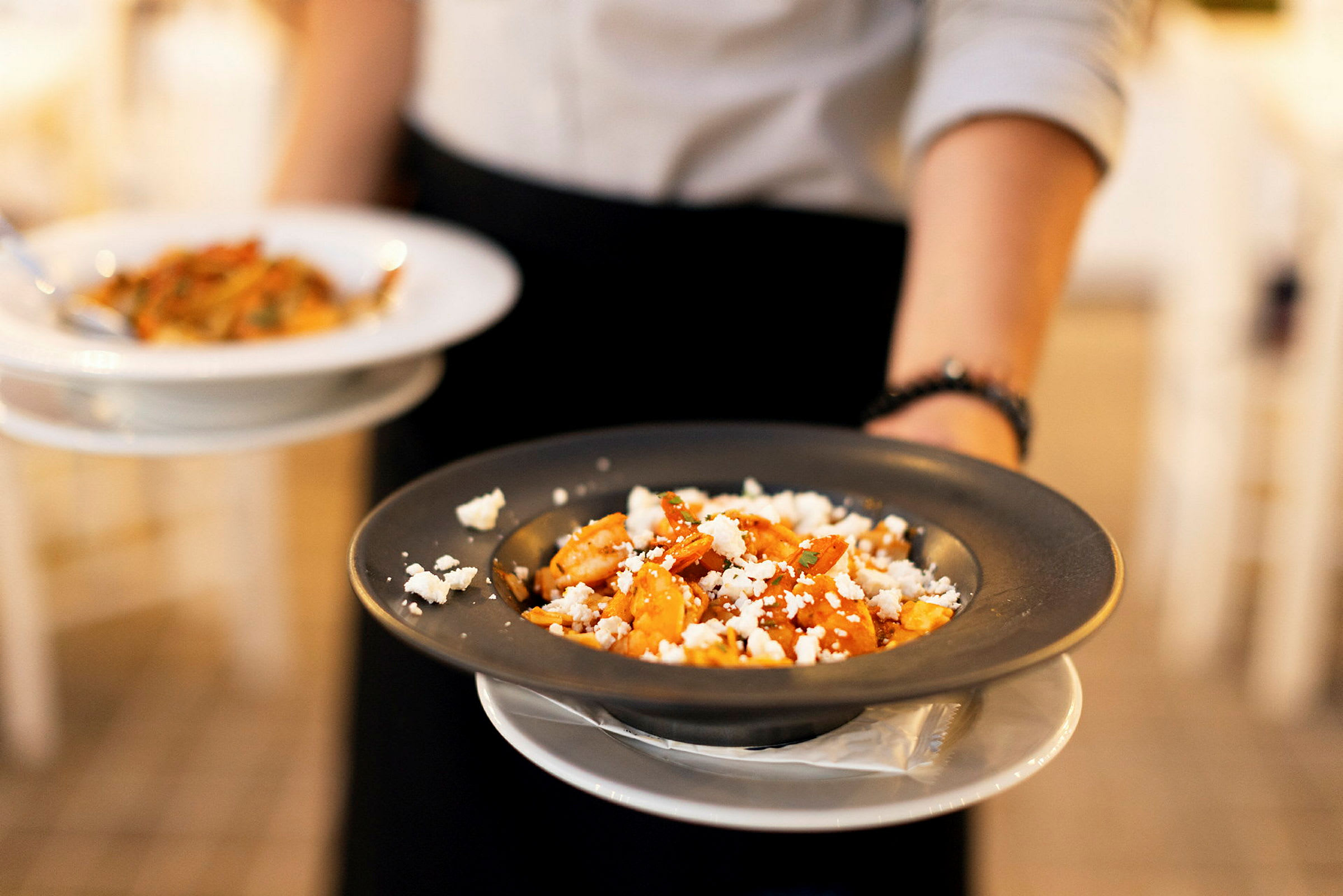 En person håller två tallrikar med pasta. (AI-genererad text)