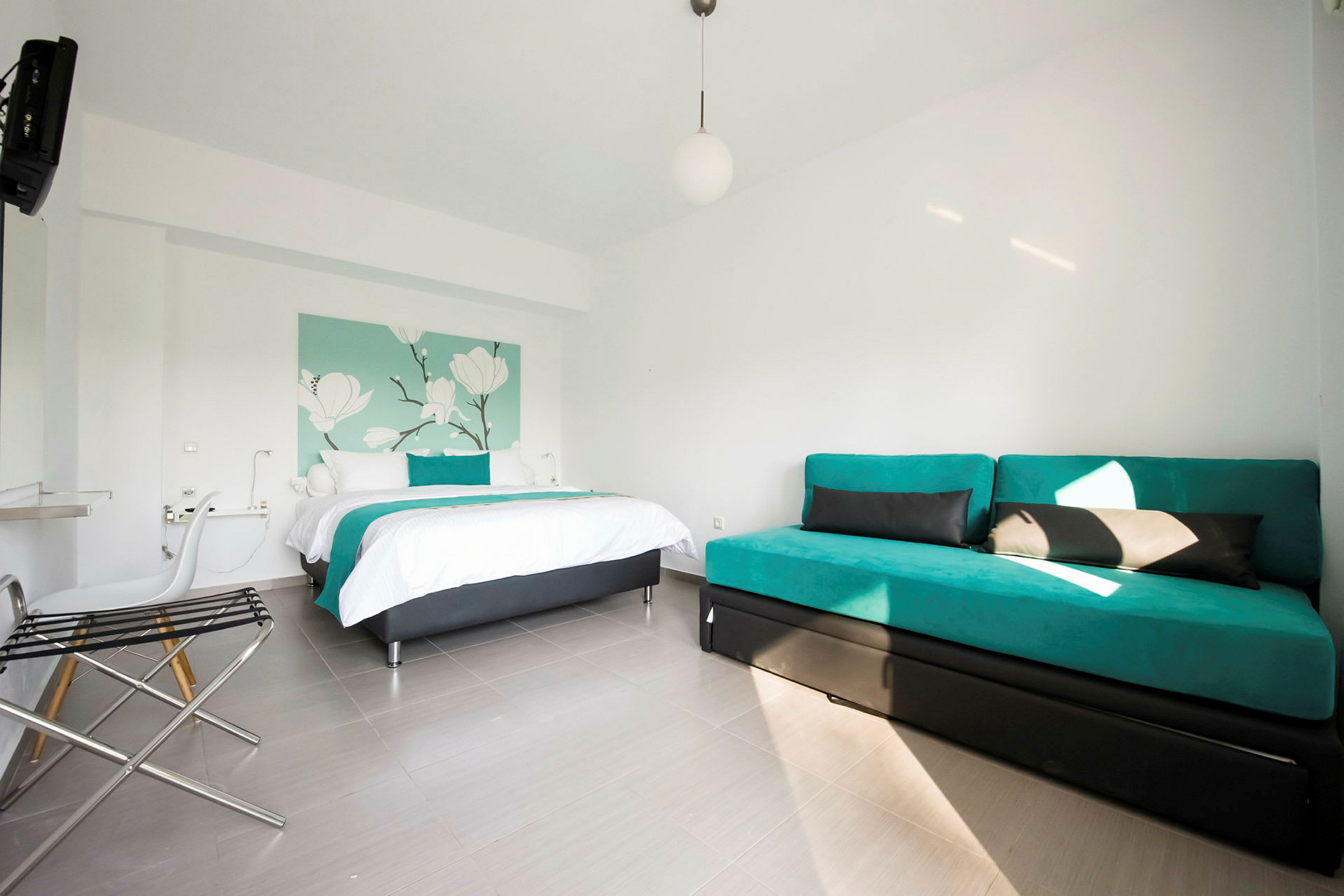 Ett hotellrum med en säng och en soffa, inrett i ljusa färger. (AI-genererad text)