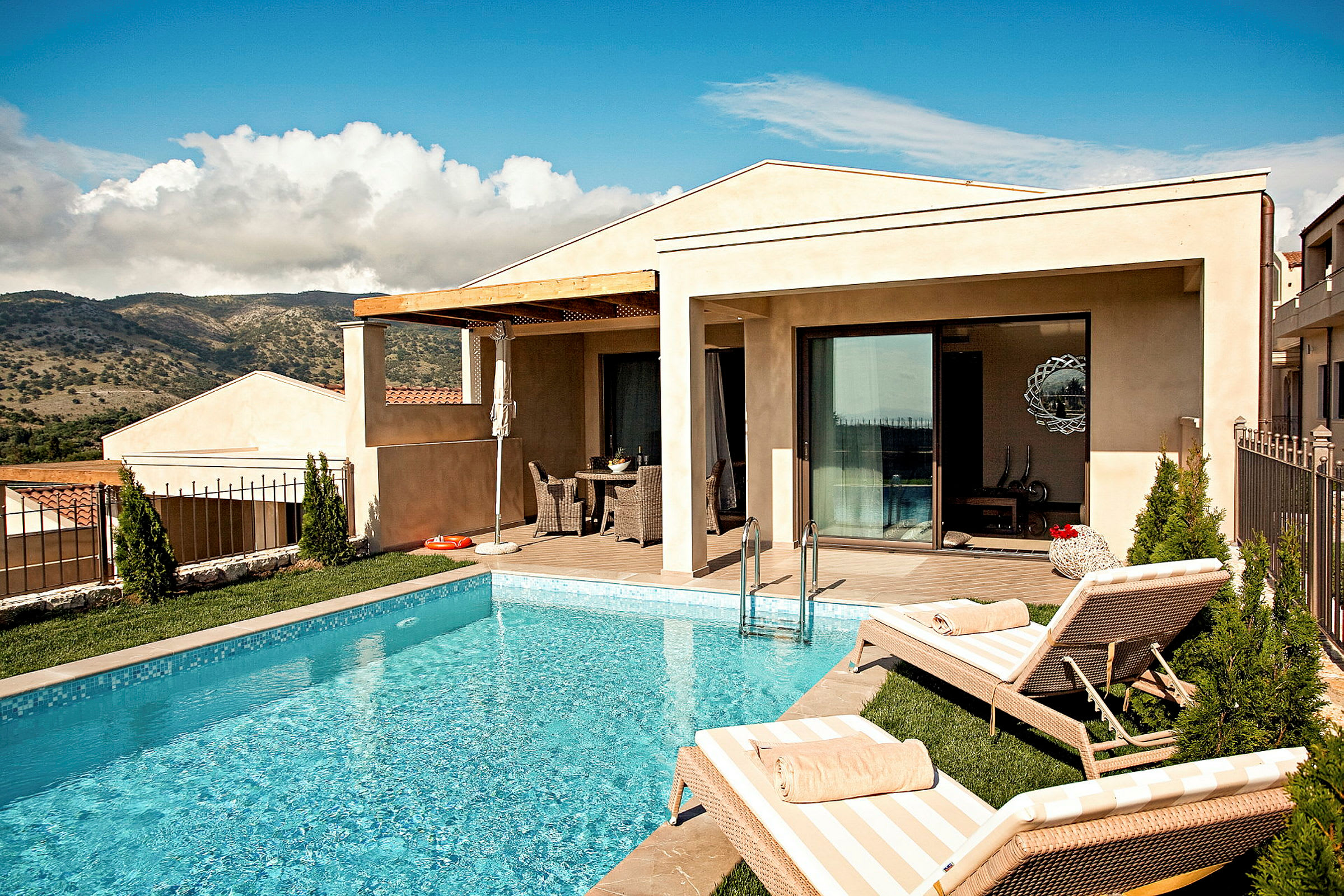 En villa med pool och solstolar framför en naturskön utsikt. (AI-genererad text)