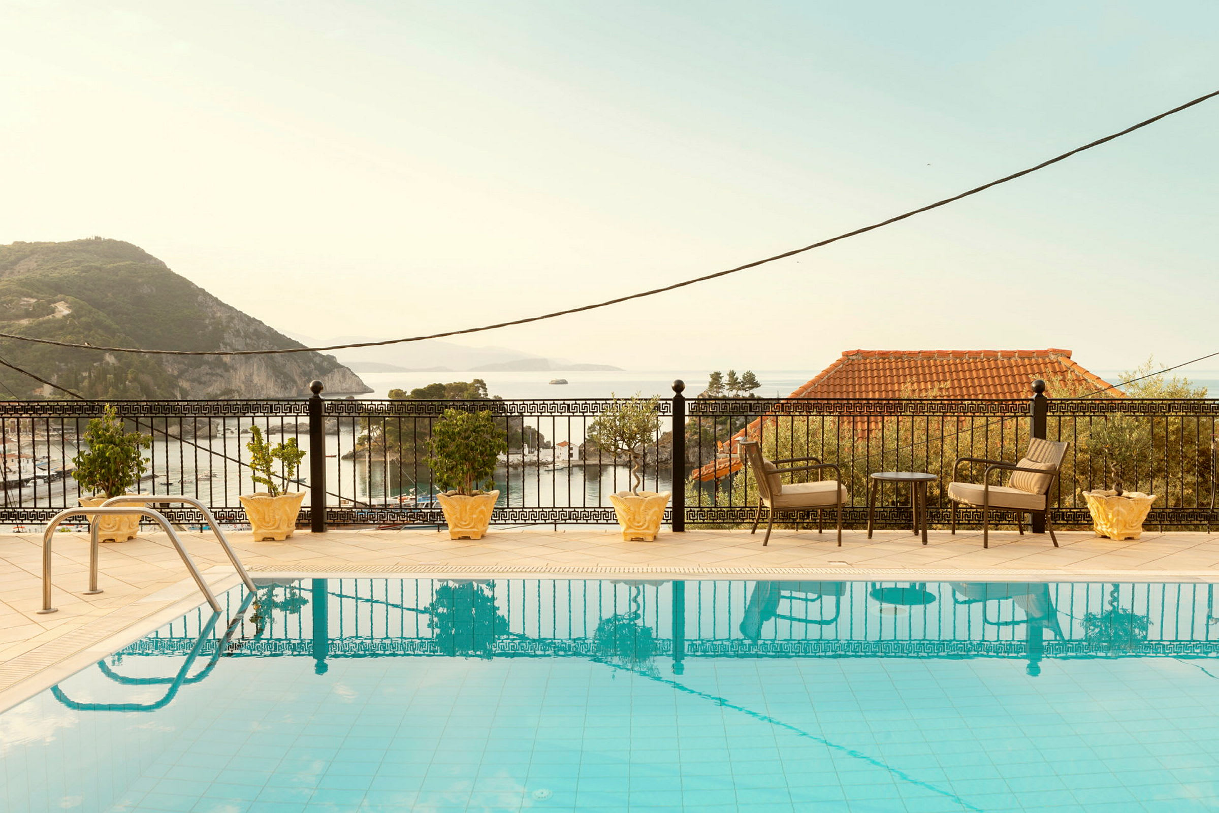 Utomhuspool med havsutsikt och sittplatser på terrassen. (AI-genererad text)