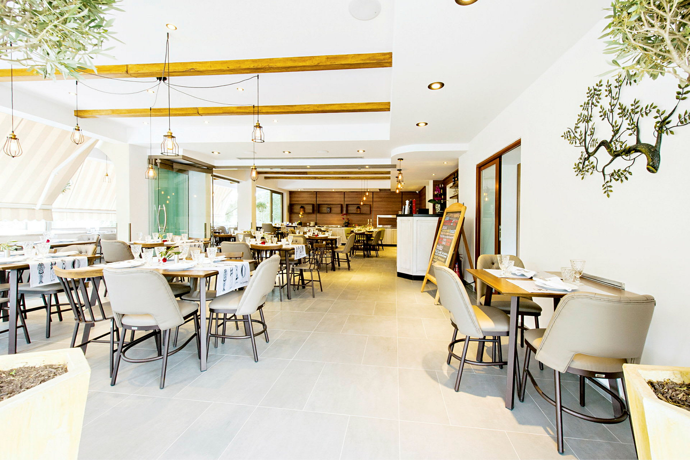 Ett ljust och modernt restaurangområde med dukade bord och stolar. (AI-genererad text)