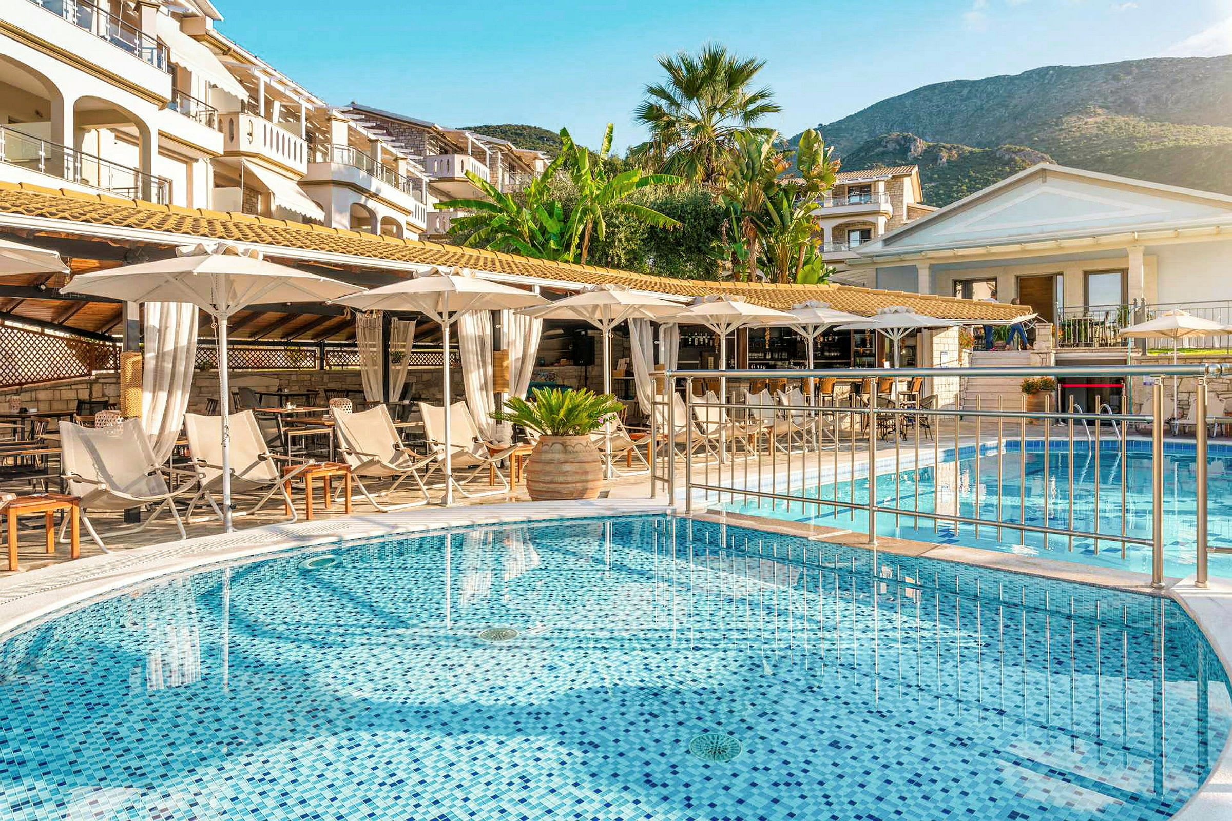 Hotellpoolområde med solstolar och parasoller vid byggnader. (AI-genererad text)