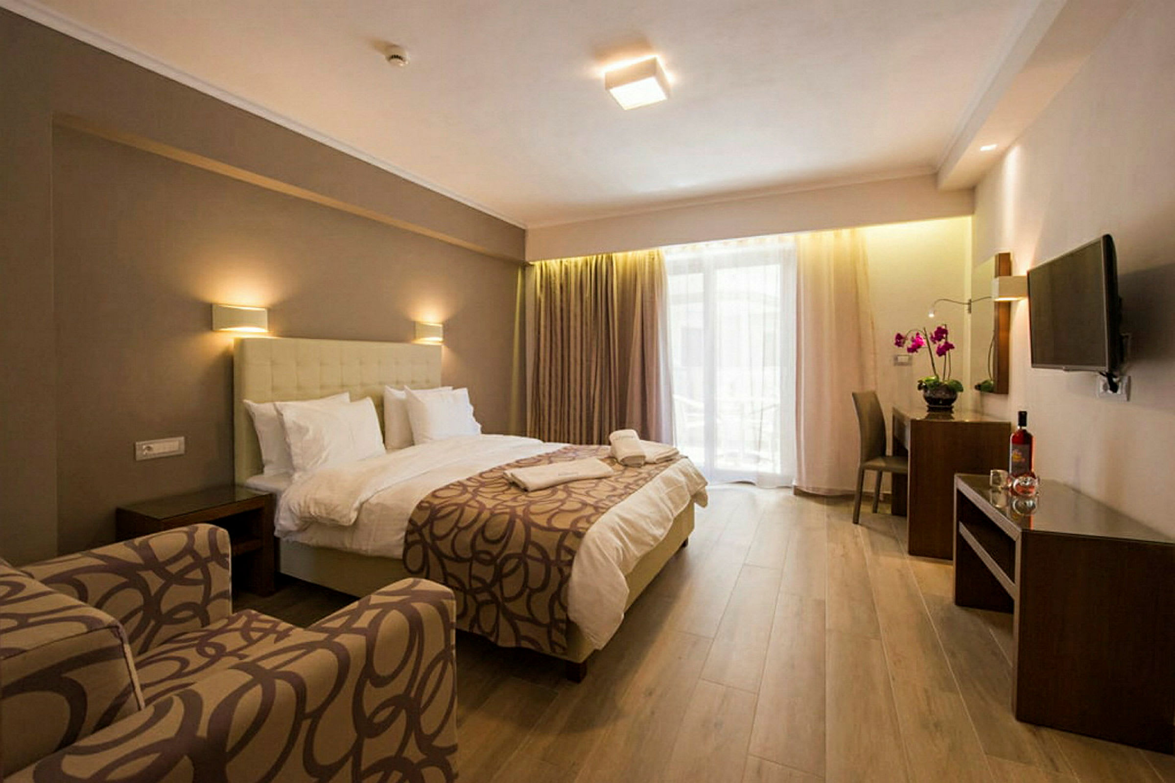 Ett hotellrum med säng, fåtölj, skrivbord och TV. (AI-genererad text)