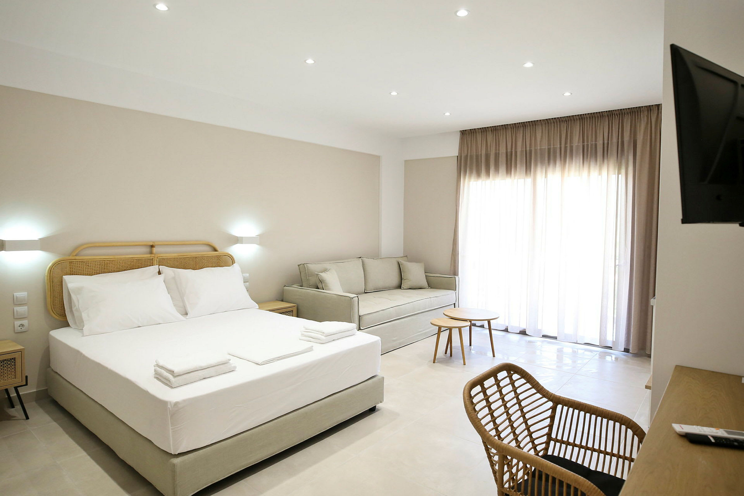 Ett hotellrum med en säng, soffa, skrivbord och stolar. (AI-genererad text)