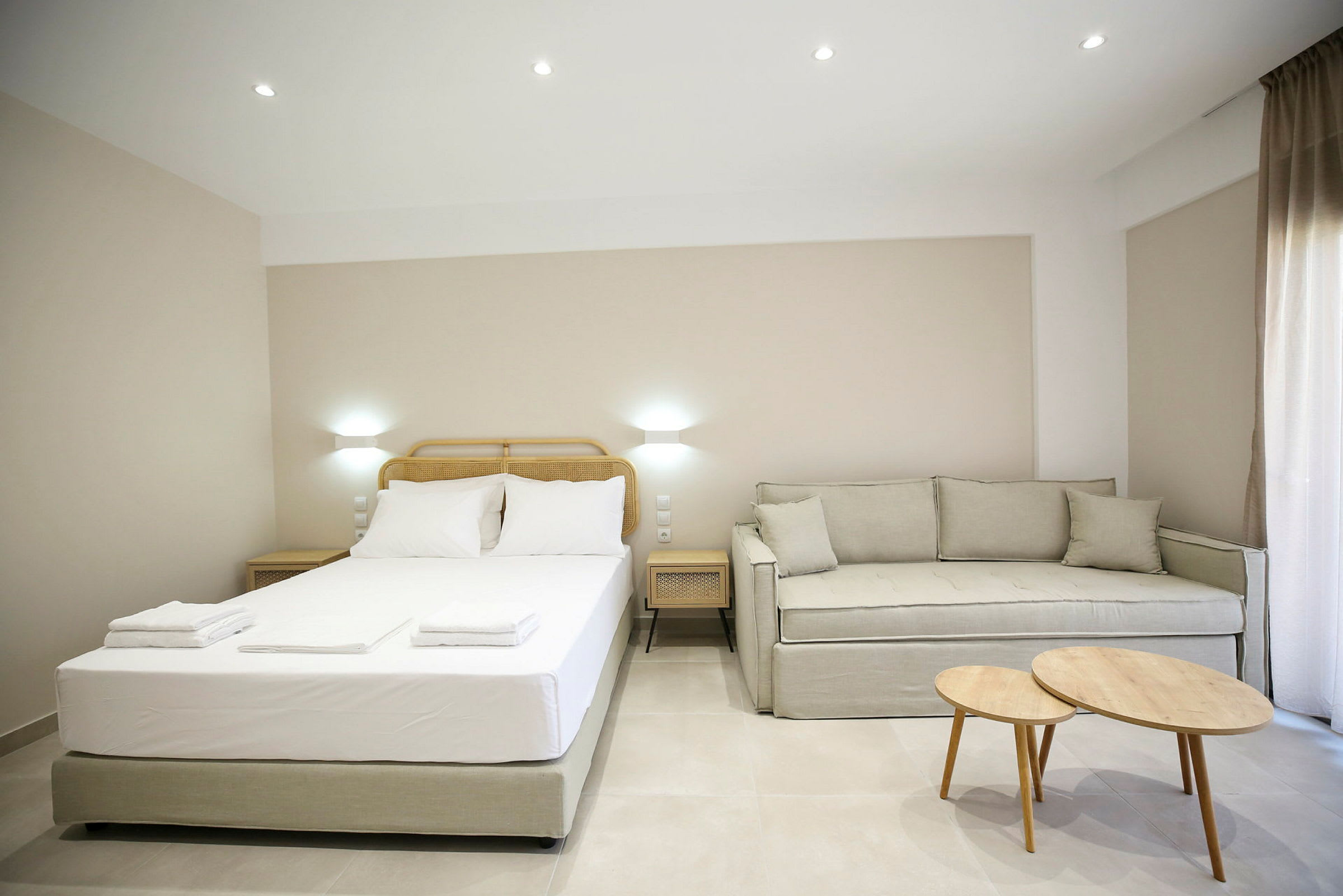 Ett hotellrum med en säng, en soffa och två bord. (AI-genererad text)