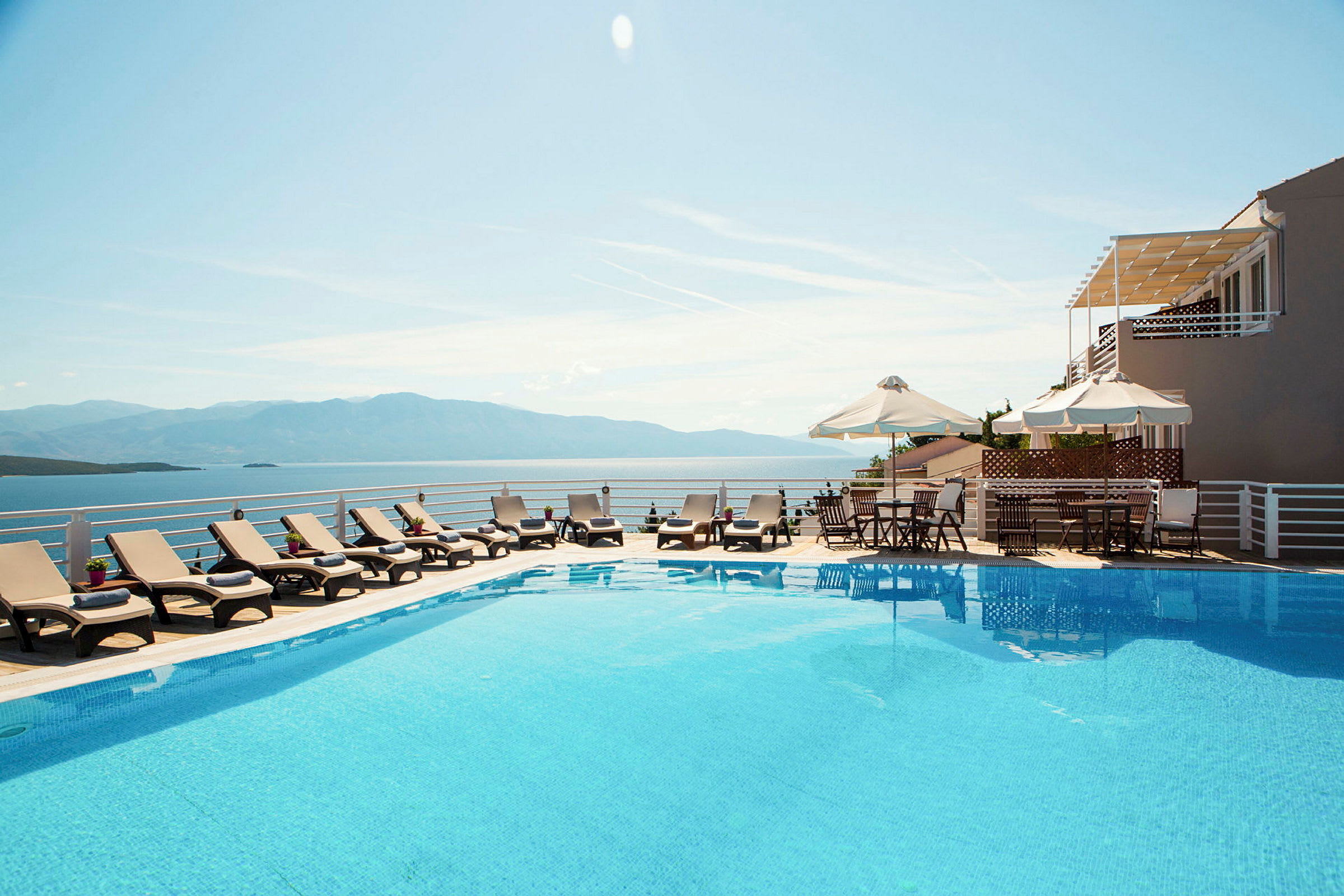 Utsikt över pool med solstolar och hav i bakgrunden. (AI-genererad text)