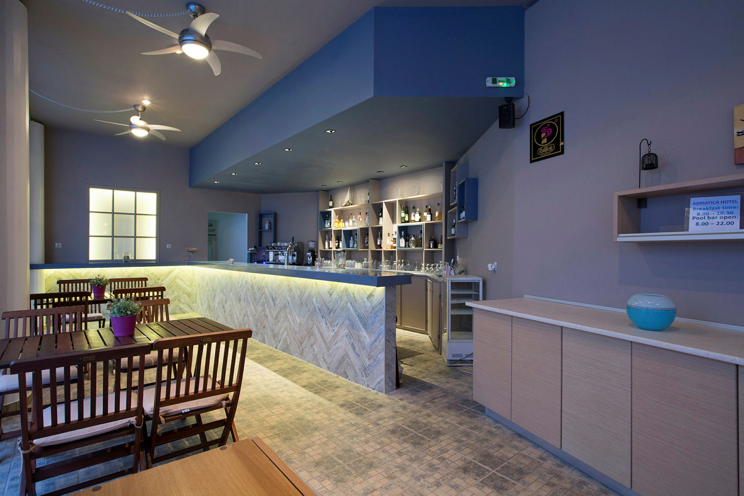 En interiörvy av en hotellbar med träbord och stolar samt en upplyst bar. (AI-genererad text)