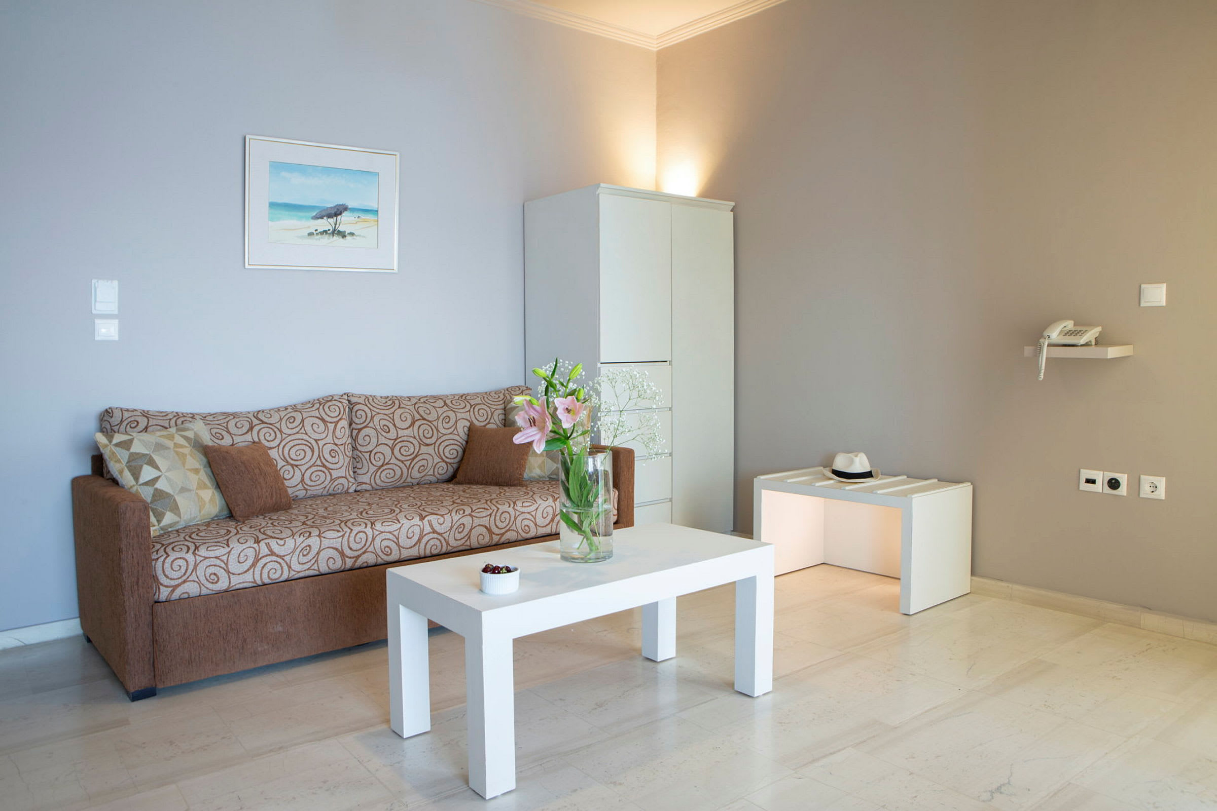 Ett vardagsrum med soffa, vit rektangulär bord, och skåp. (AI-genererad text)