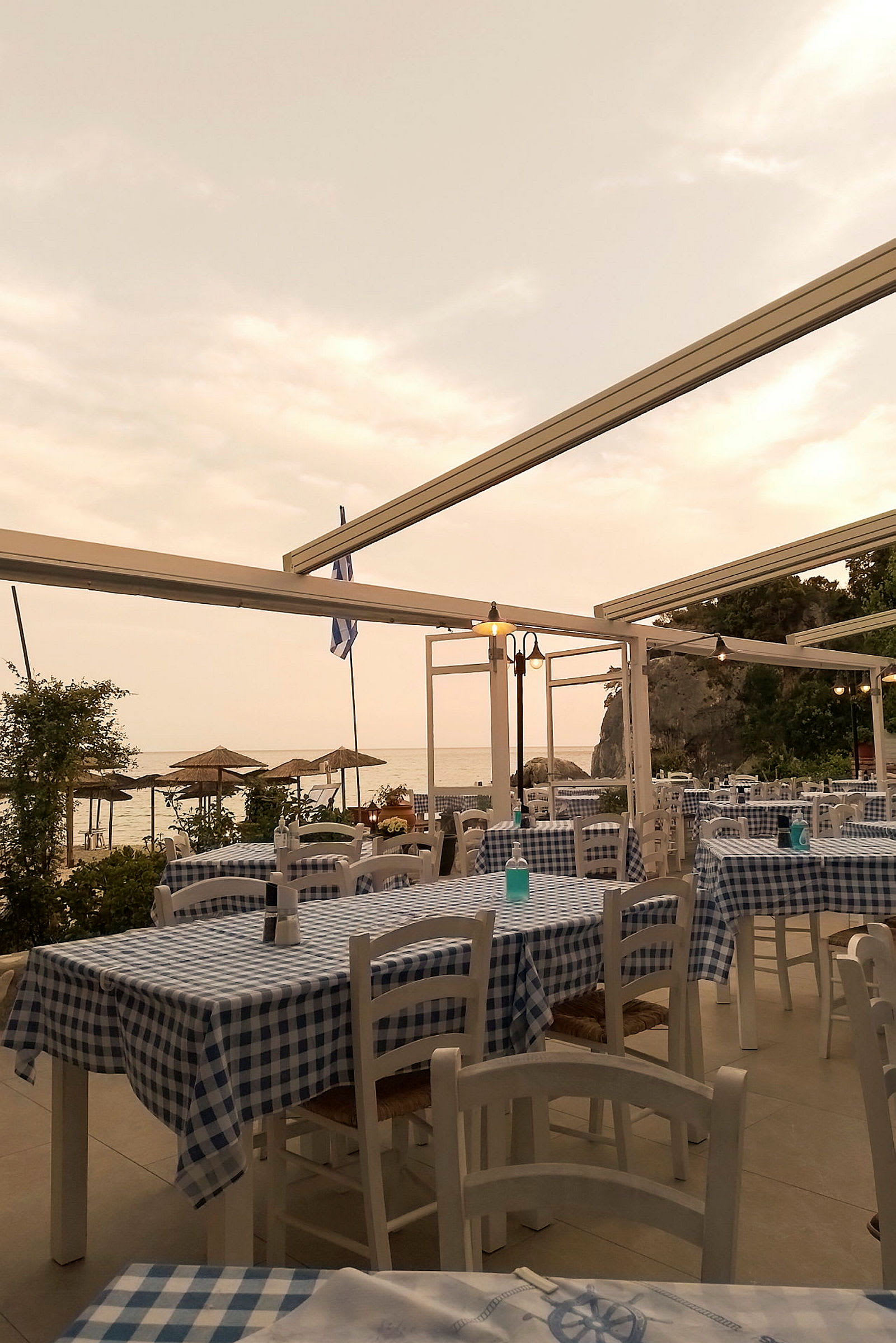Restaurang med rutiga borddukar och havsutsikt under molnig himmel. (AI-genererad text)